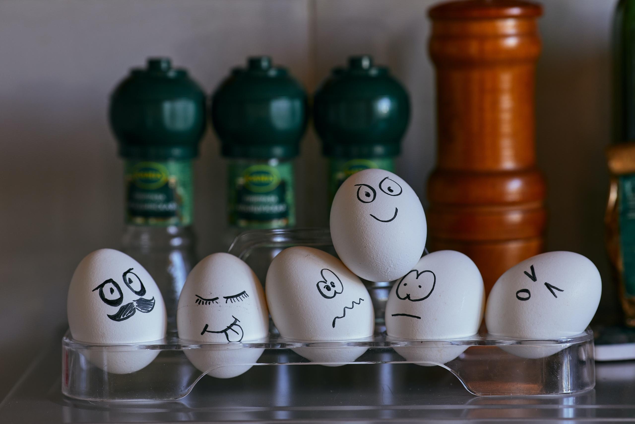 Zes eieren op het schap beelden verschillende emoties uit