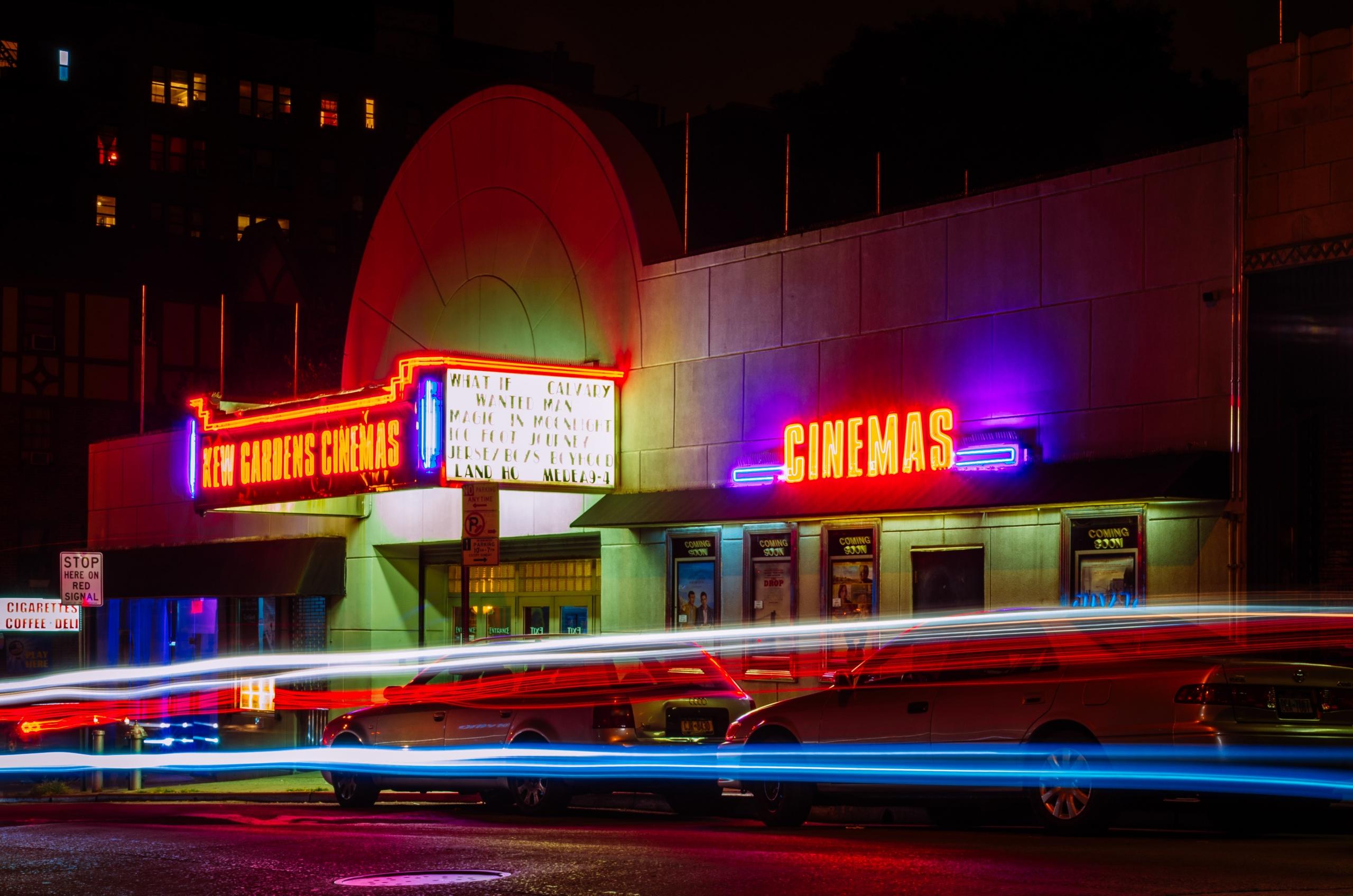 biscoop met cinemas op de voorgevel, felle neonlichten en auto's die ervoor op straat staan