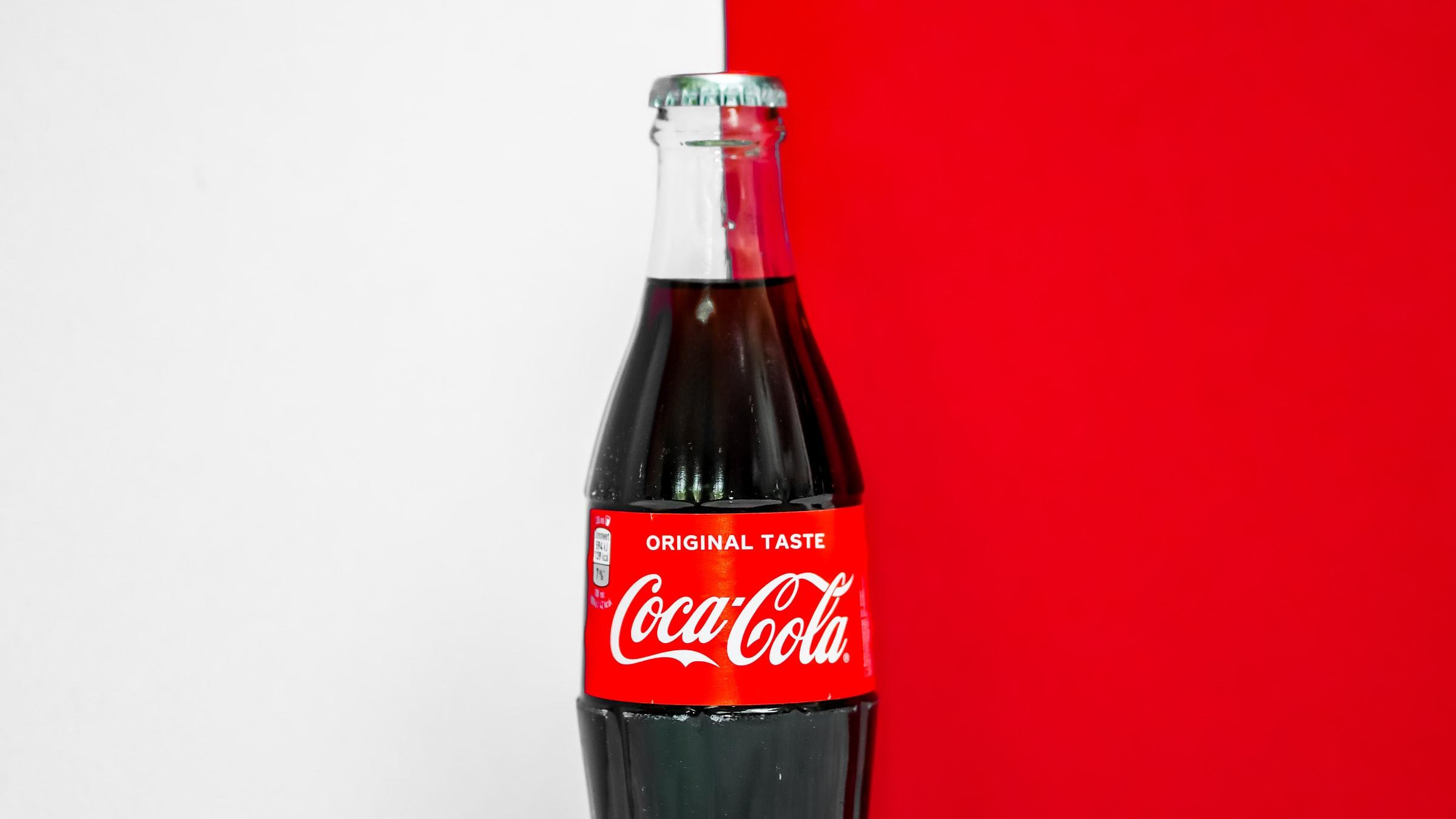 Een fles Coca-Cola tegen een wit-rode achtergrond