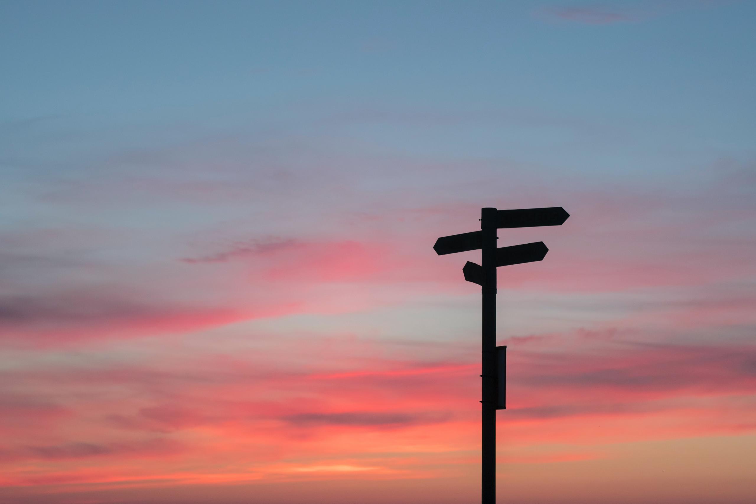 Een wegwijzer bij zonsondergang