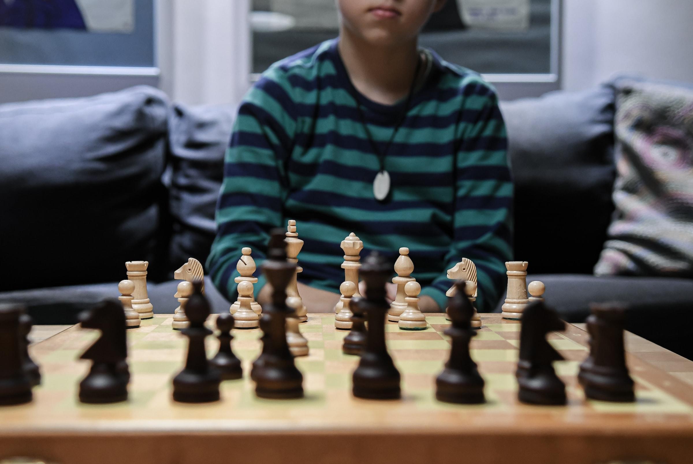 Jongen achter schaakbord met stukken