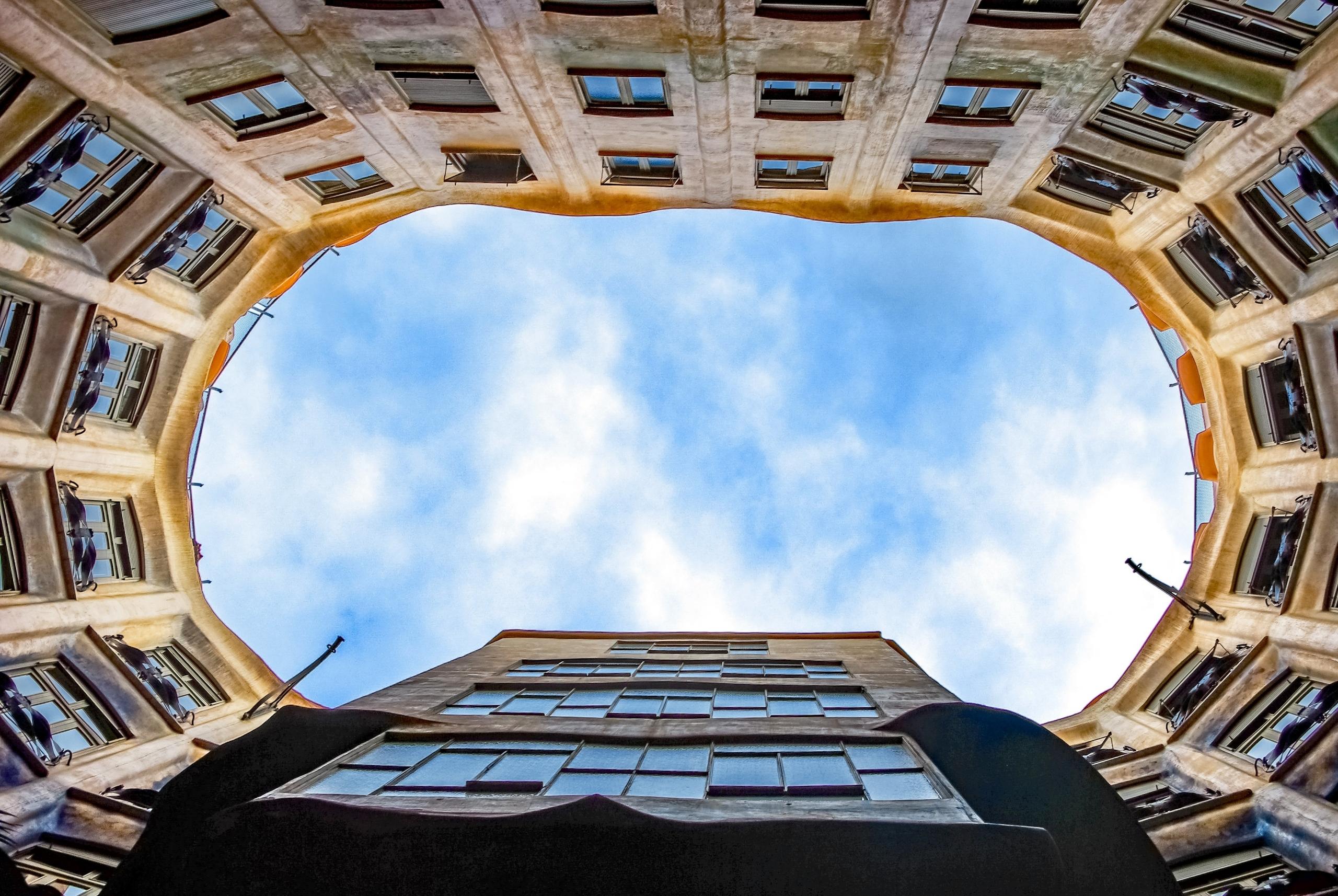 aanzicht van onder middenin rond gebouw met blauwe lucht