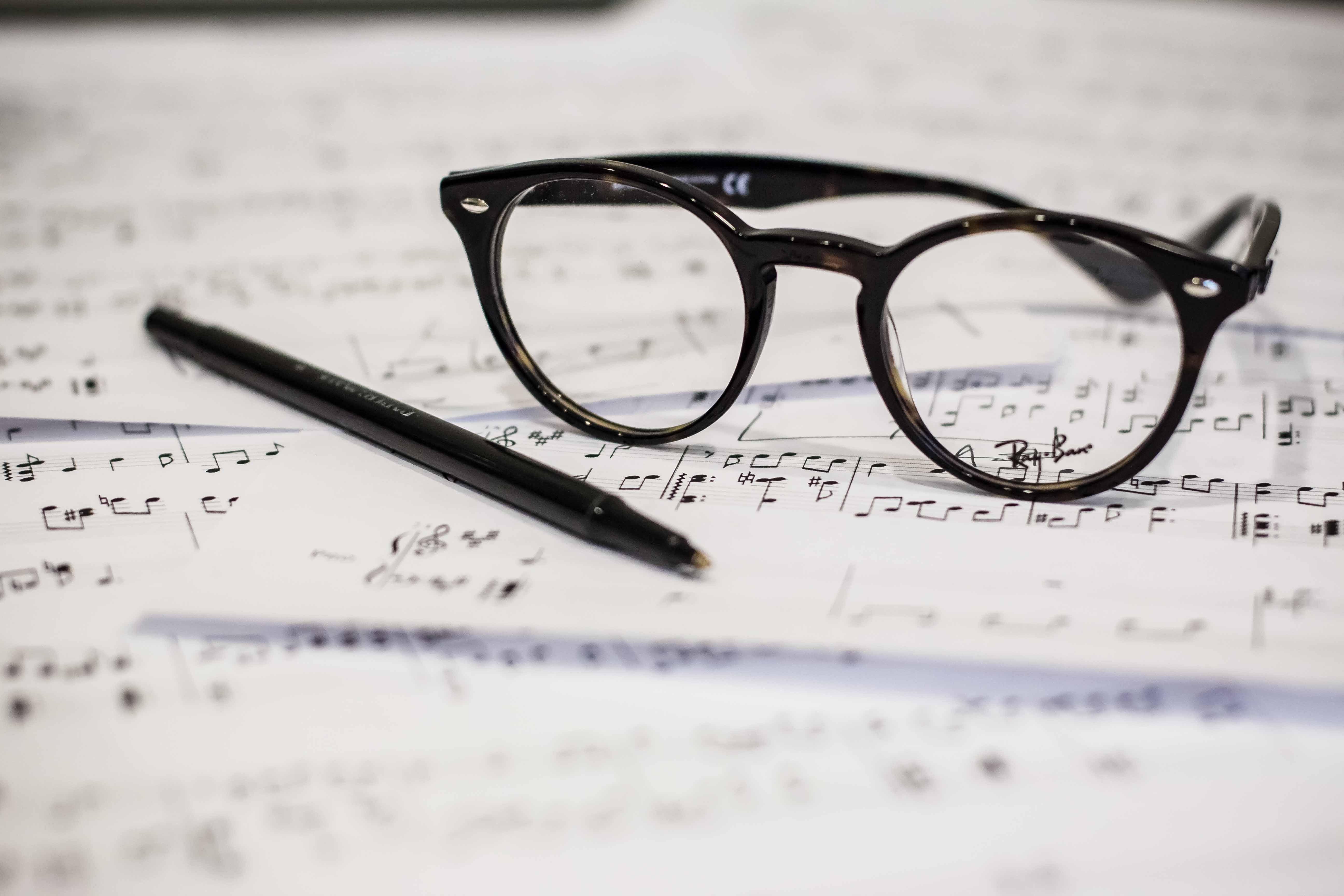 Een bril rust op bladen met bladmuziek
