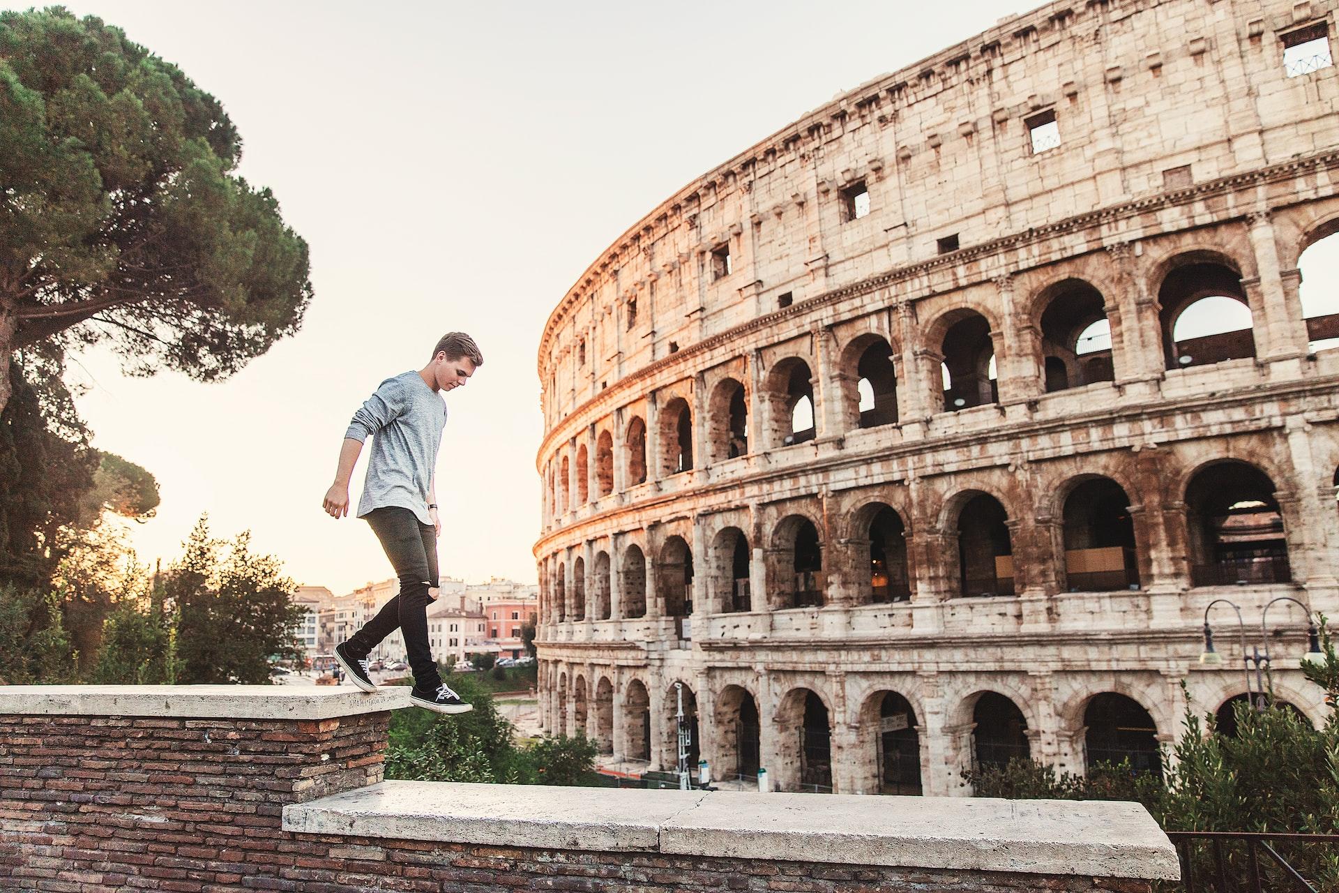 man springt op muur voor colosseum
