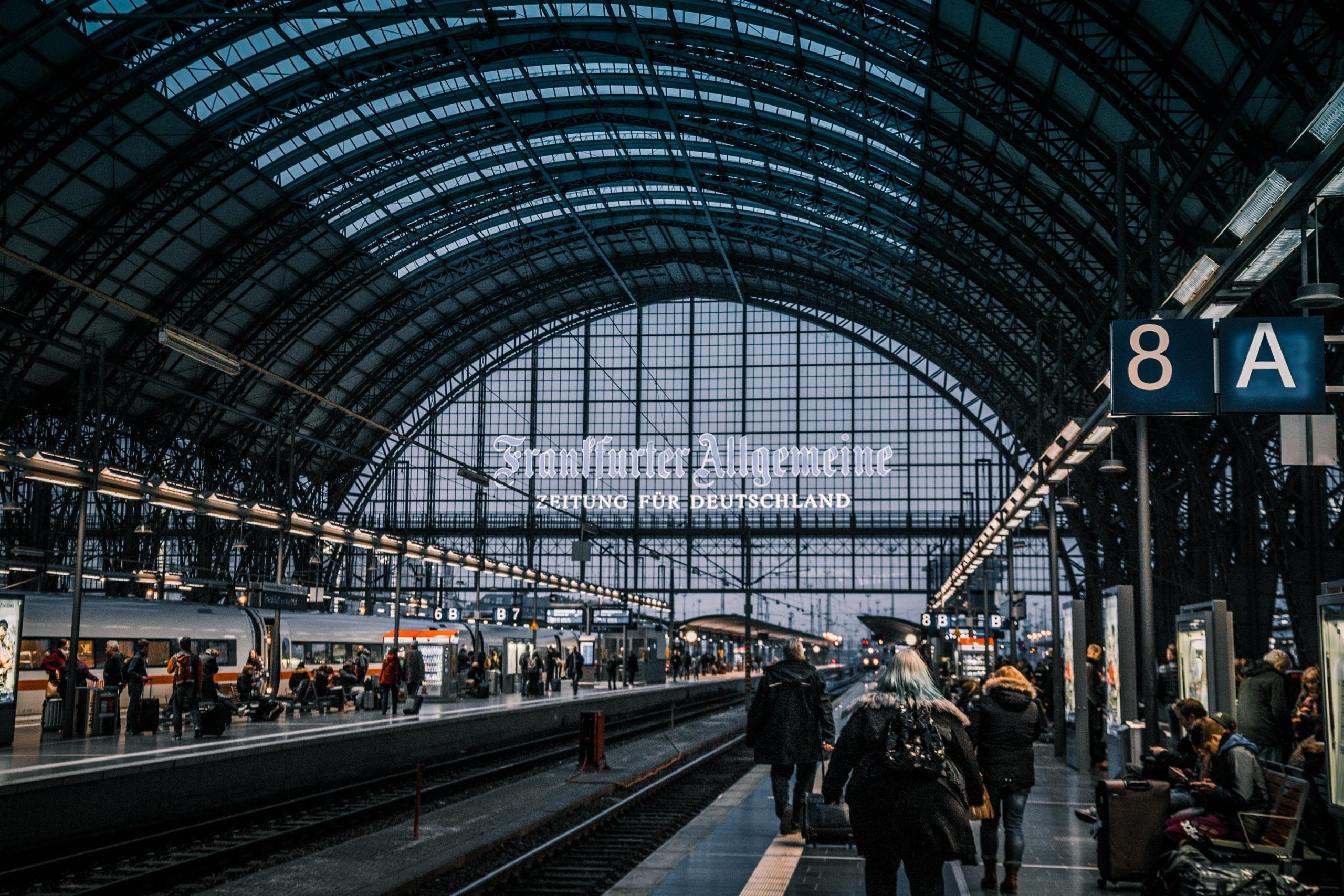 Mensen lopen op perron in hal van treinstation