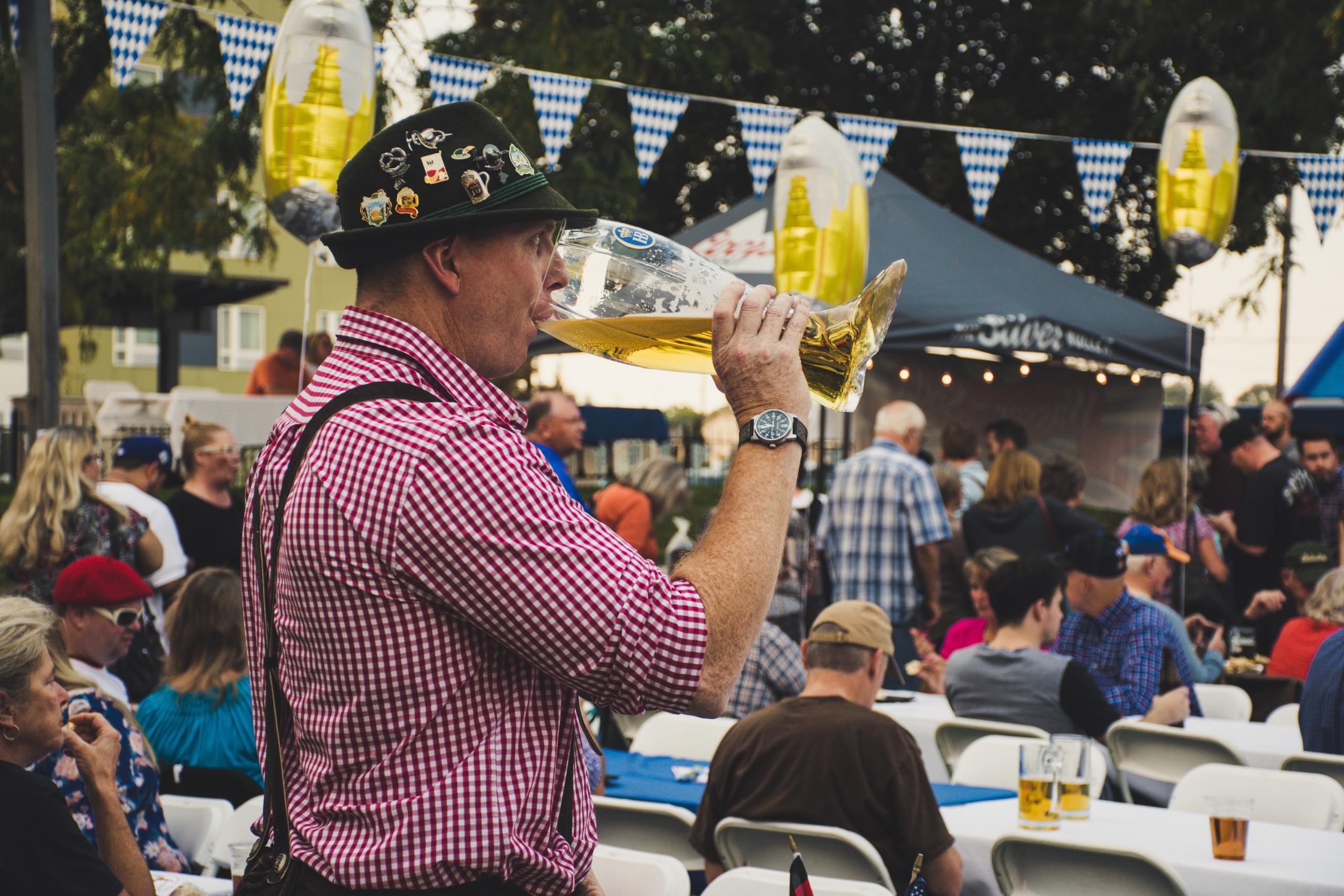 Man drinkt bier in traditionele Duitse kledij in zaal met mensen