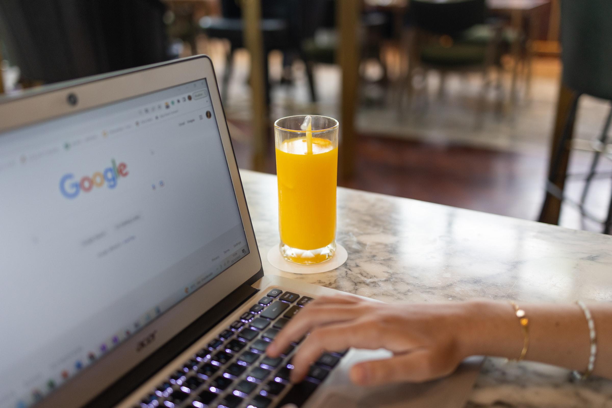 Vrouw achter laptop met glas sinaasappelsap