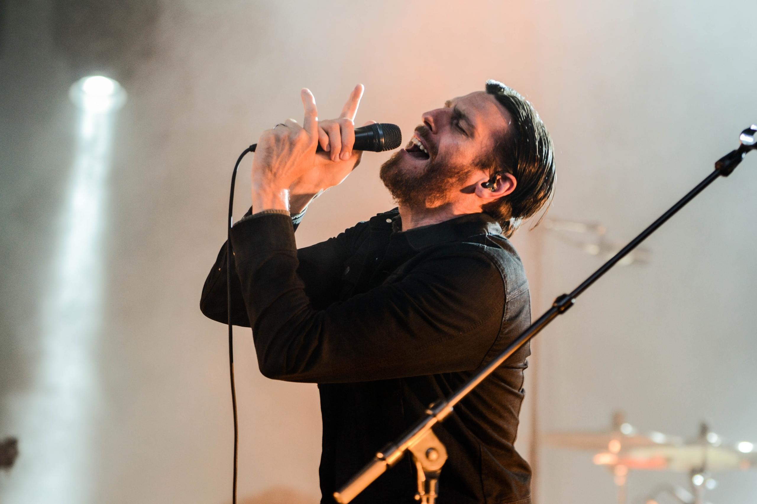 Man zingt in een microfoon op een podium.