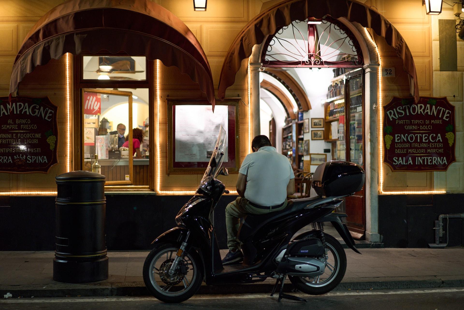 je zit op een vespa buiten een restaurant in Italië
