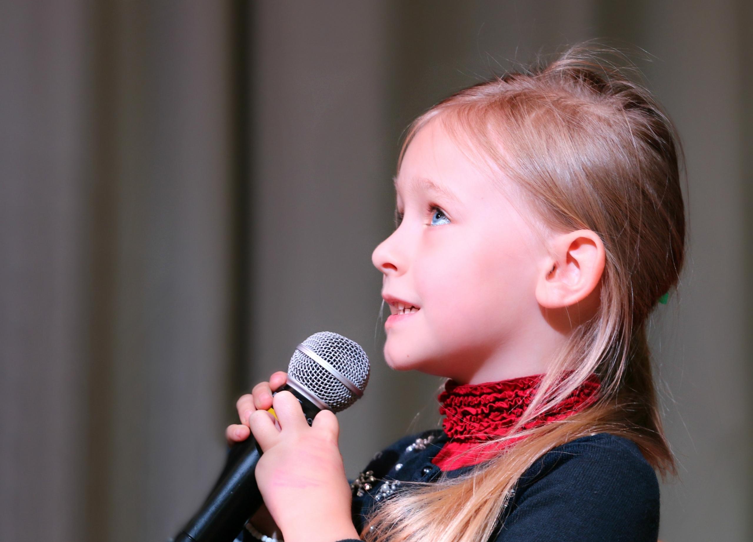 Kind zingt met microfoon in haar hand.