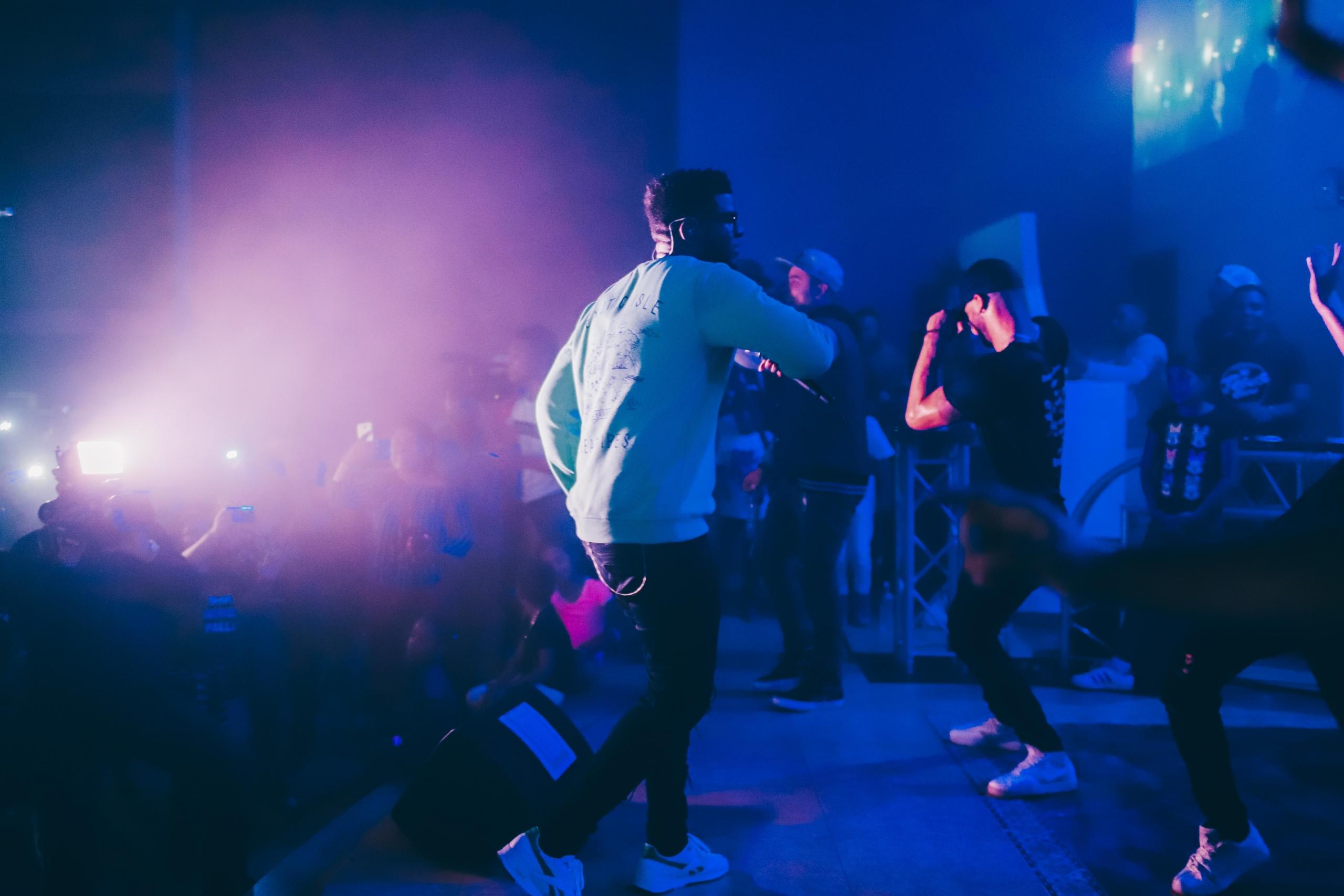 Mannen treden op op podium, zingen en dansen.