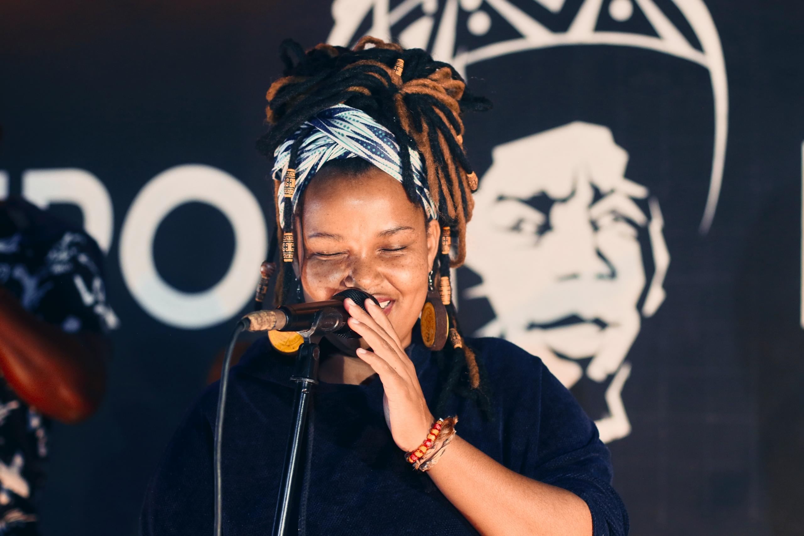 Vrouw zingt op een podium in een microfoon in een standaard.