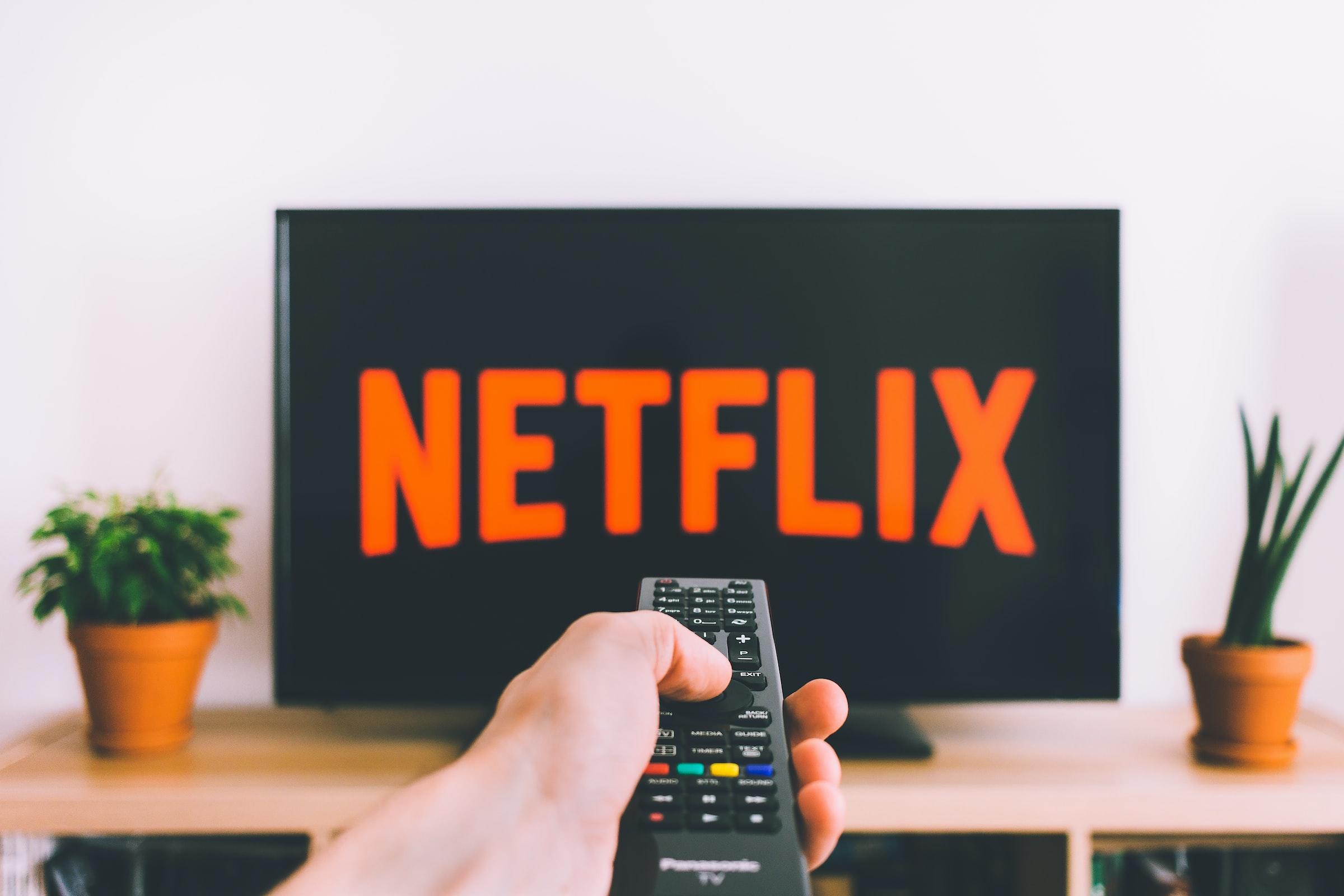 Hand met afstandsbediening die afstemt op Netflix
