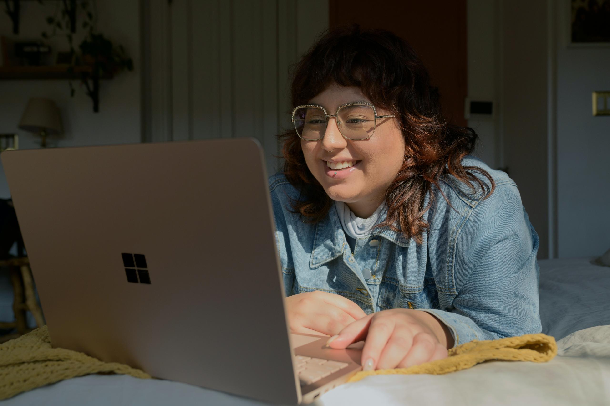 Vrouw studeert met een glimlach achter haal laptop.