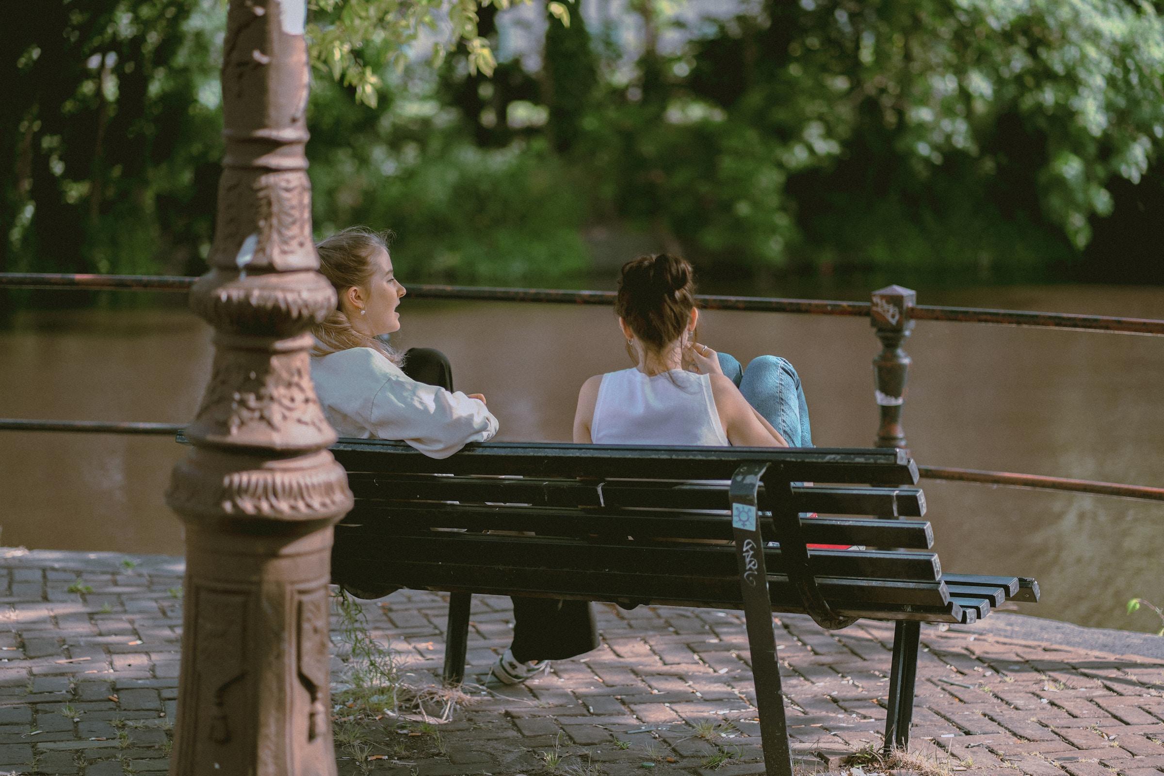 Twee vrouwen pratend op bankje aan het water