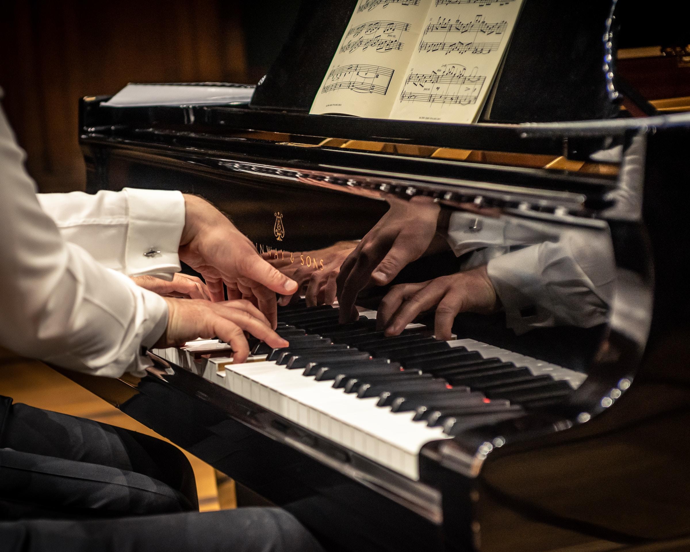 Twee samenspelende mannen op de piano, alleen handen gefotografeerd 