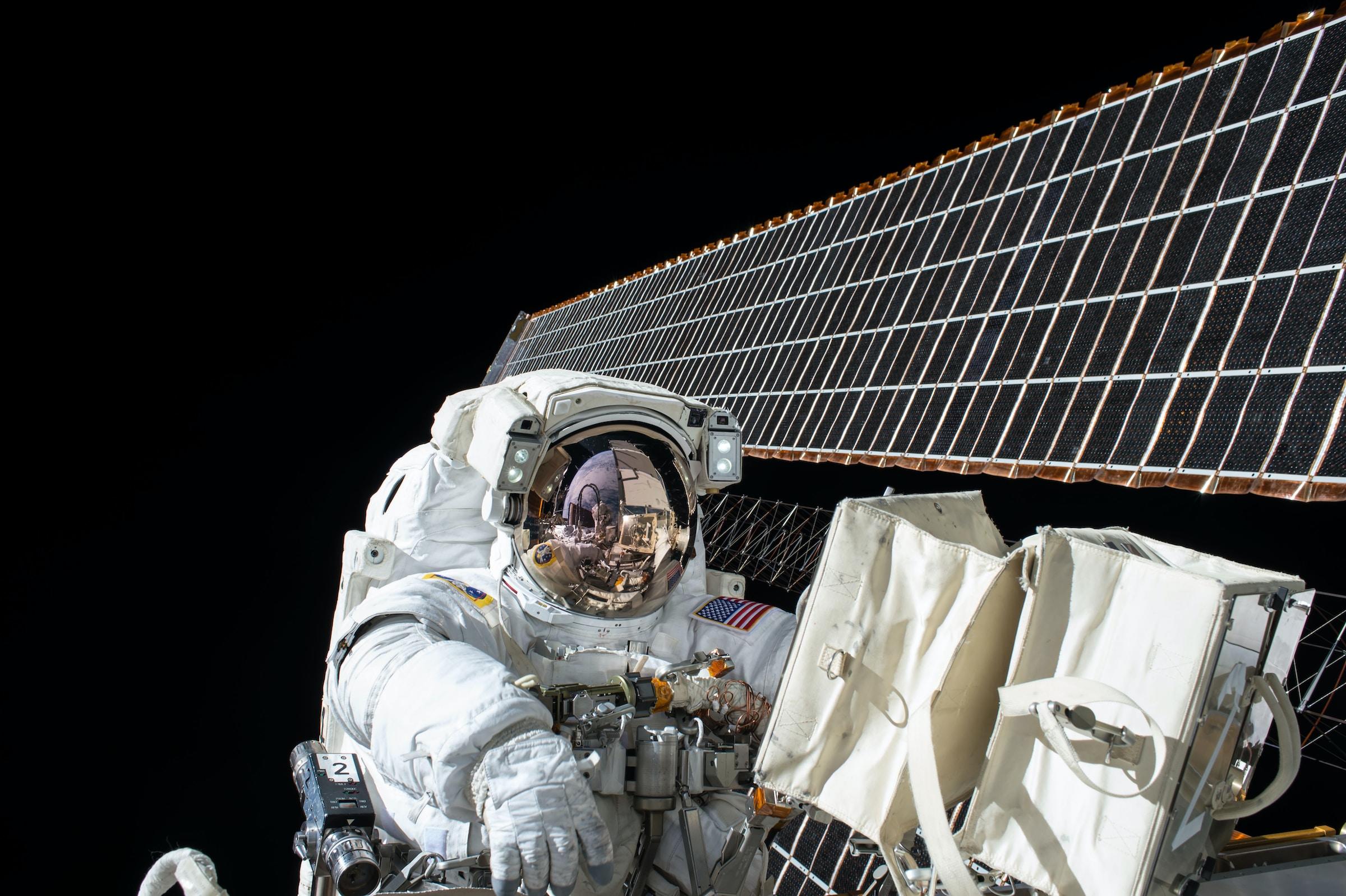 Astronaut naast een satelliet