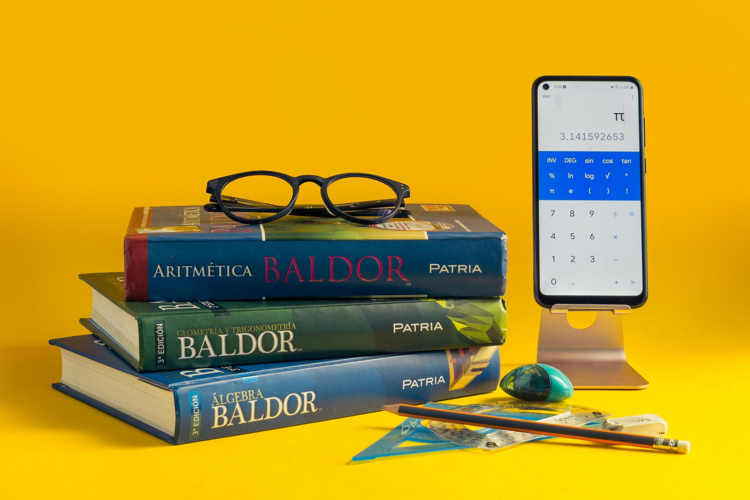 Drie wiskunde boeken en een smartphone op gele achtergrond
