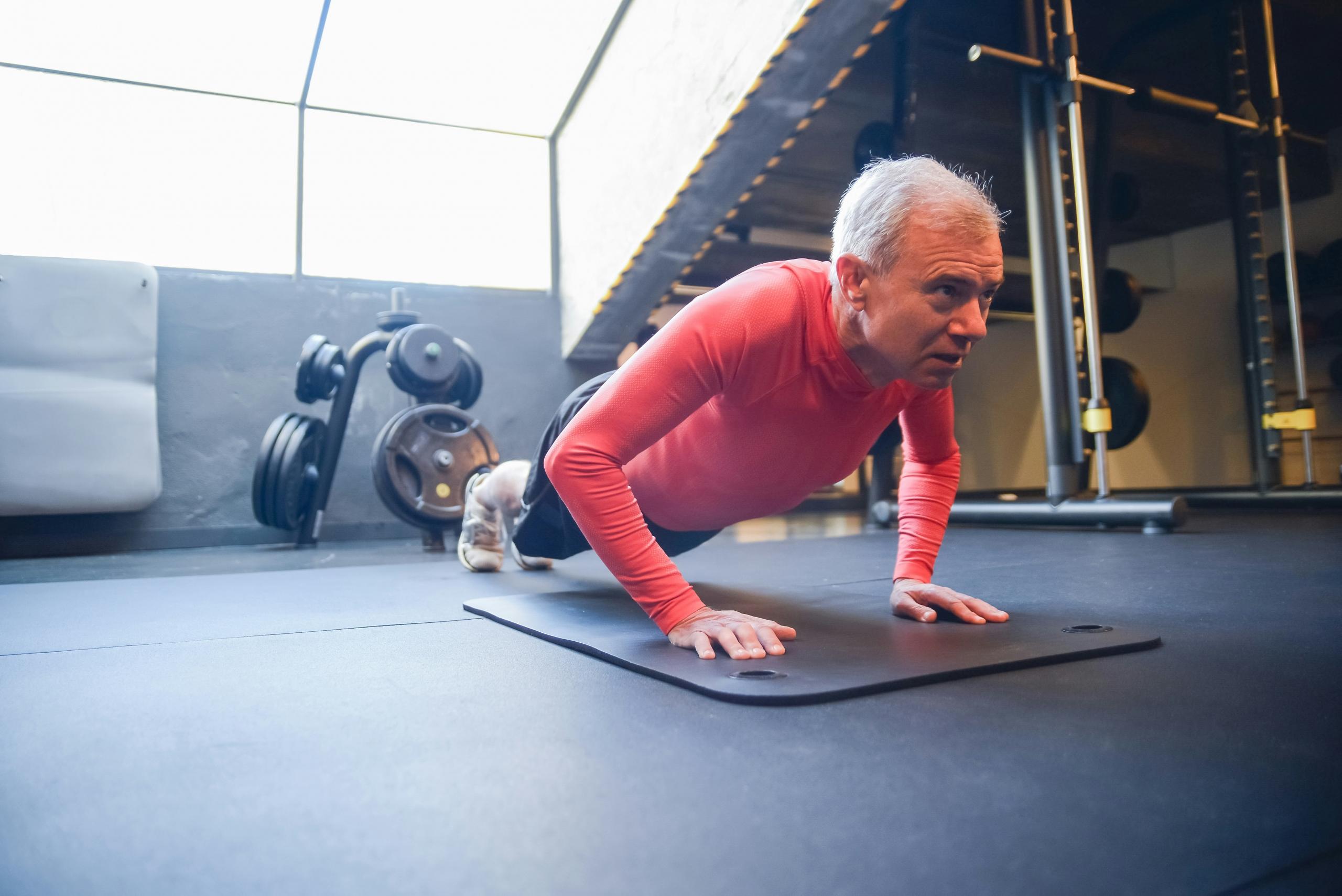 Man doet een push up op een matje in een sportschool