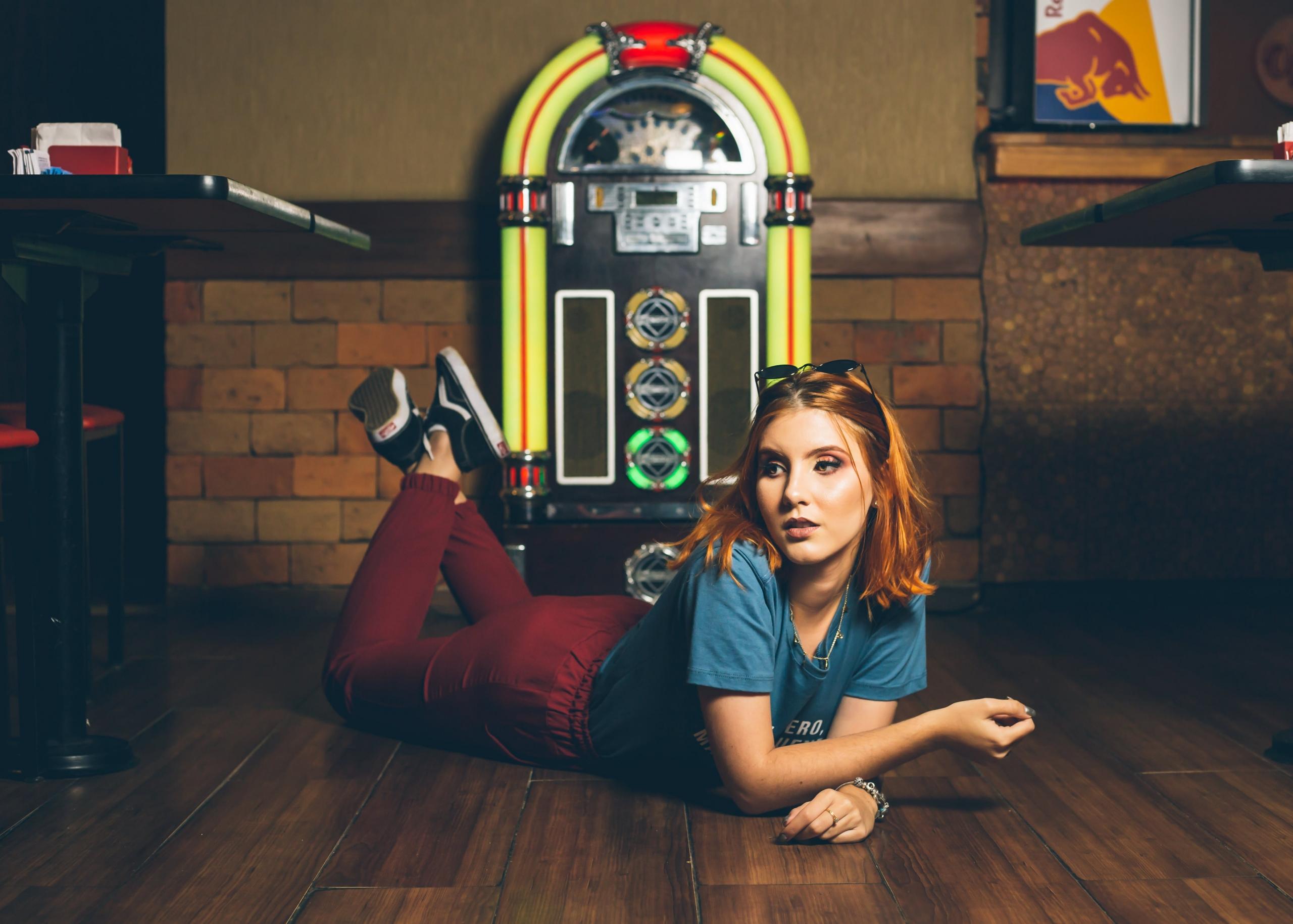 Vrouw ligt voor jukebox op de grond in een cafe.