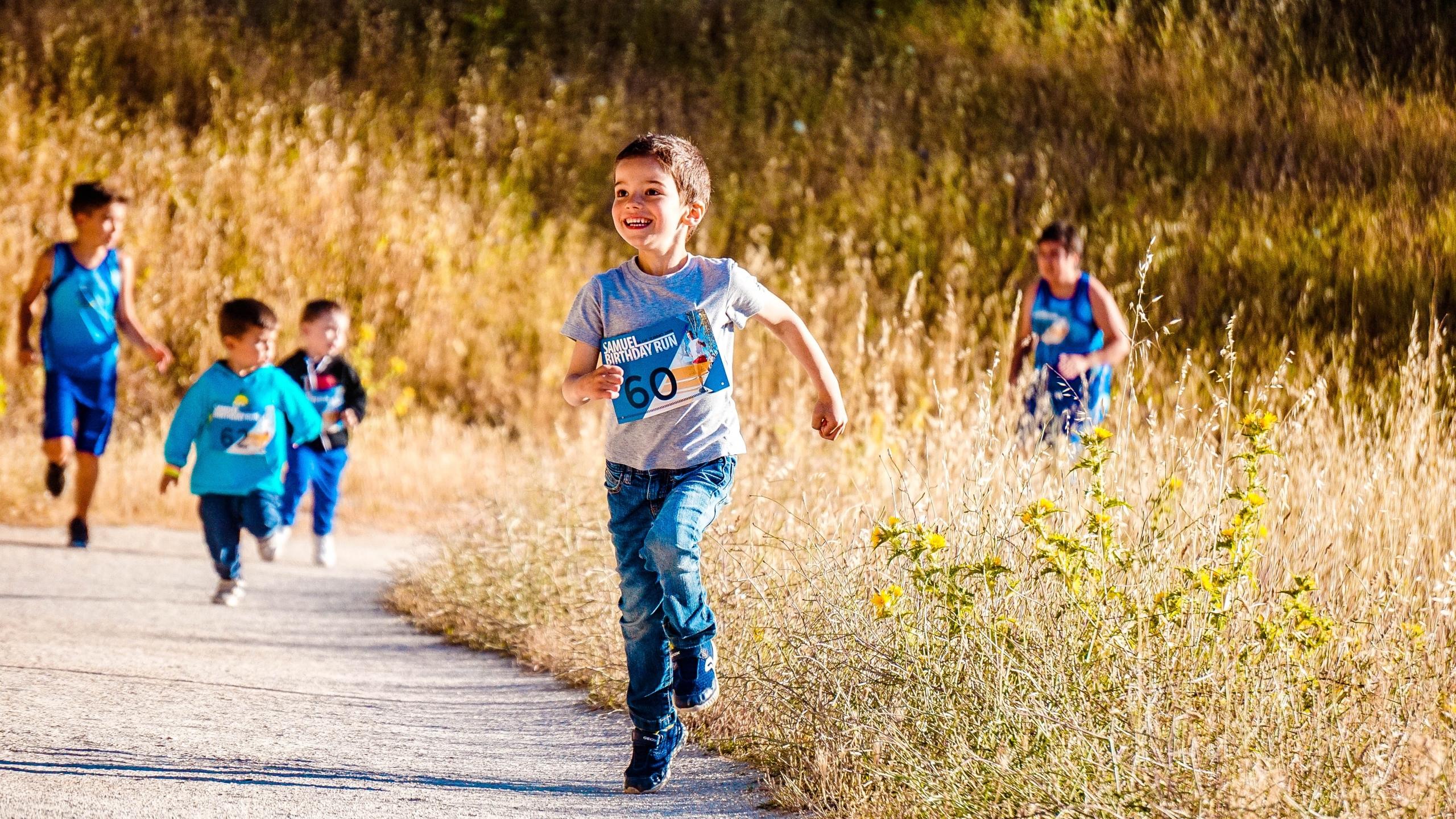 Kinderen rennen buiten op asfalt langs hoog gras