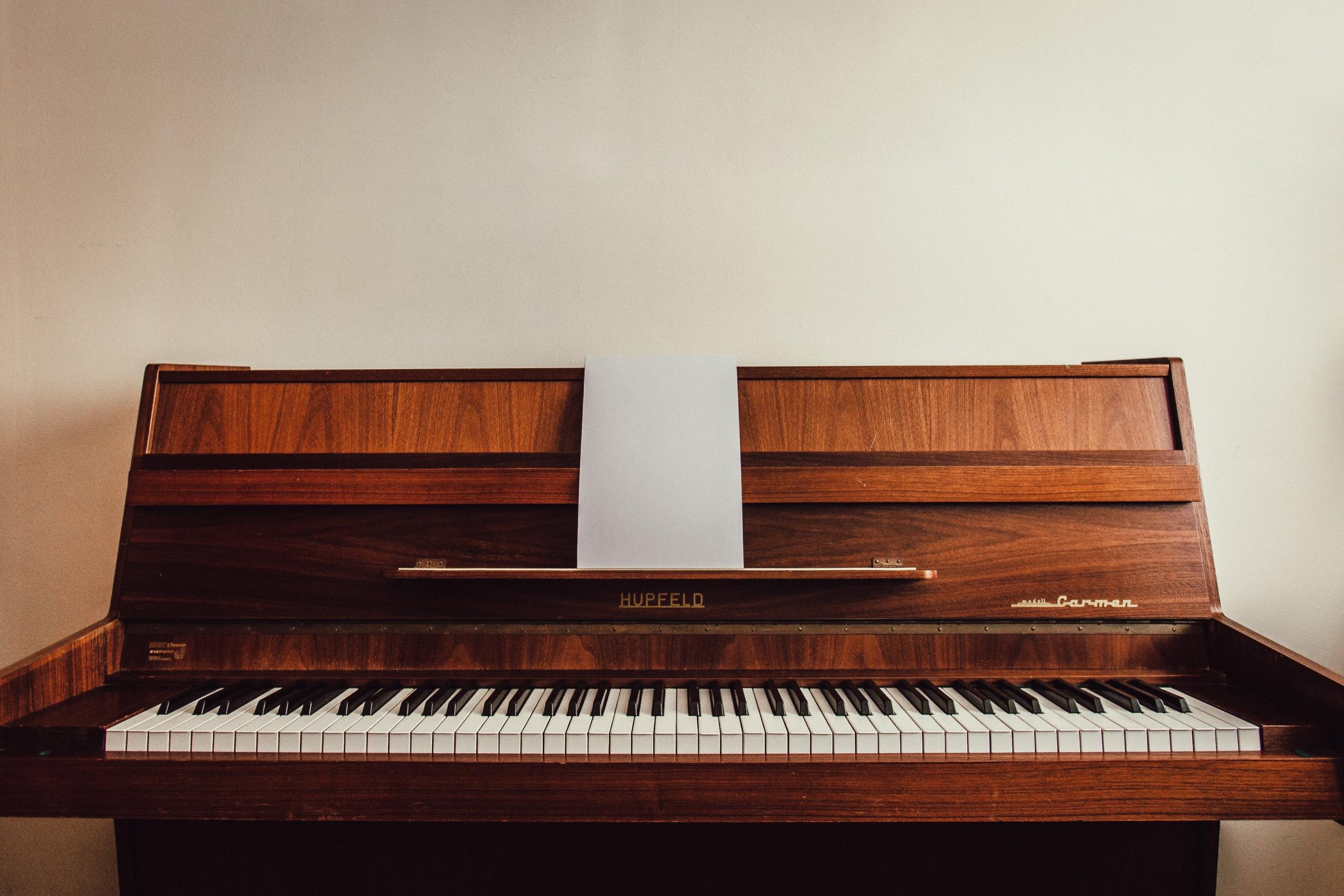 Een piano met een leeg blad muziek op de muziekstandaard in een kamer met een vintage sfeer.