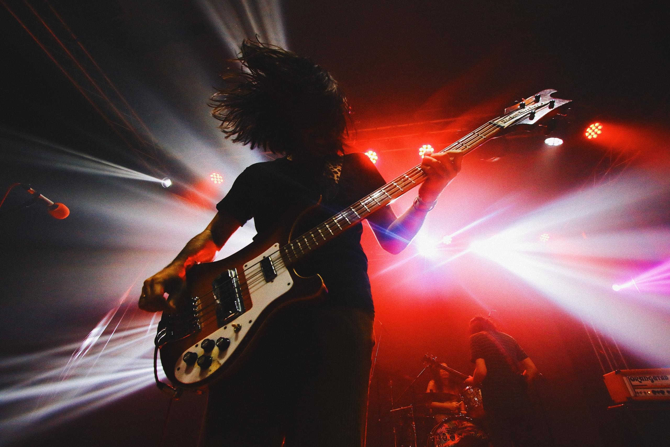 Een bassist speelt op een podium met dynamische verlichting.