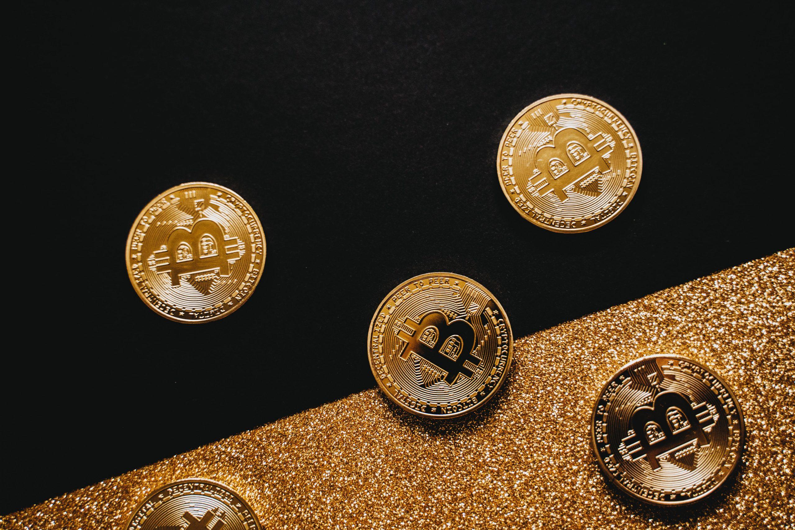 Gouden Bitcoin-munten op een zwarte achtergrond met gouden glitters.