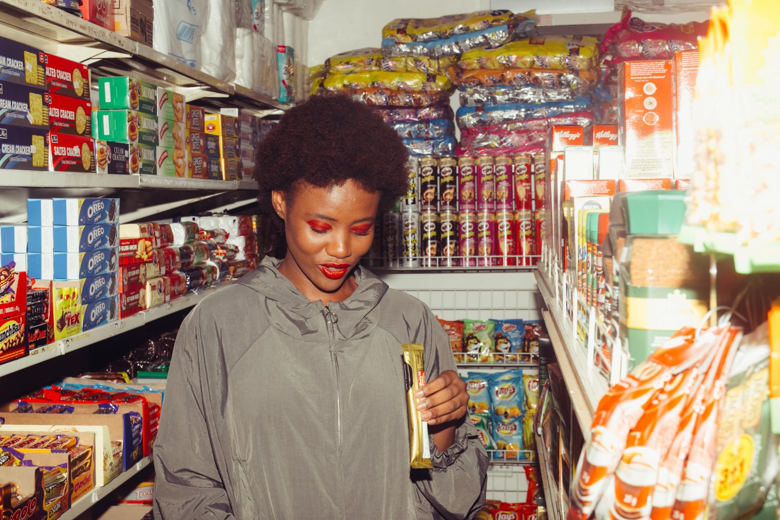 Een vrouw in een supermarkt kijkt naar een product in haar hand.