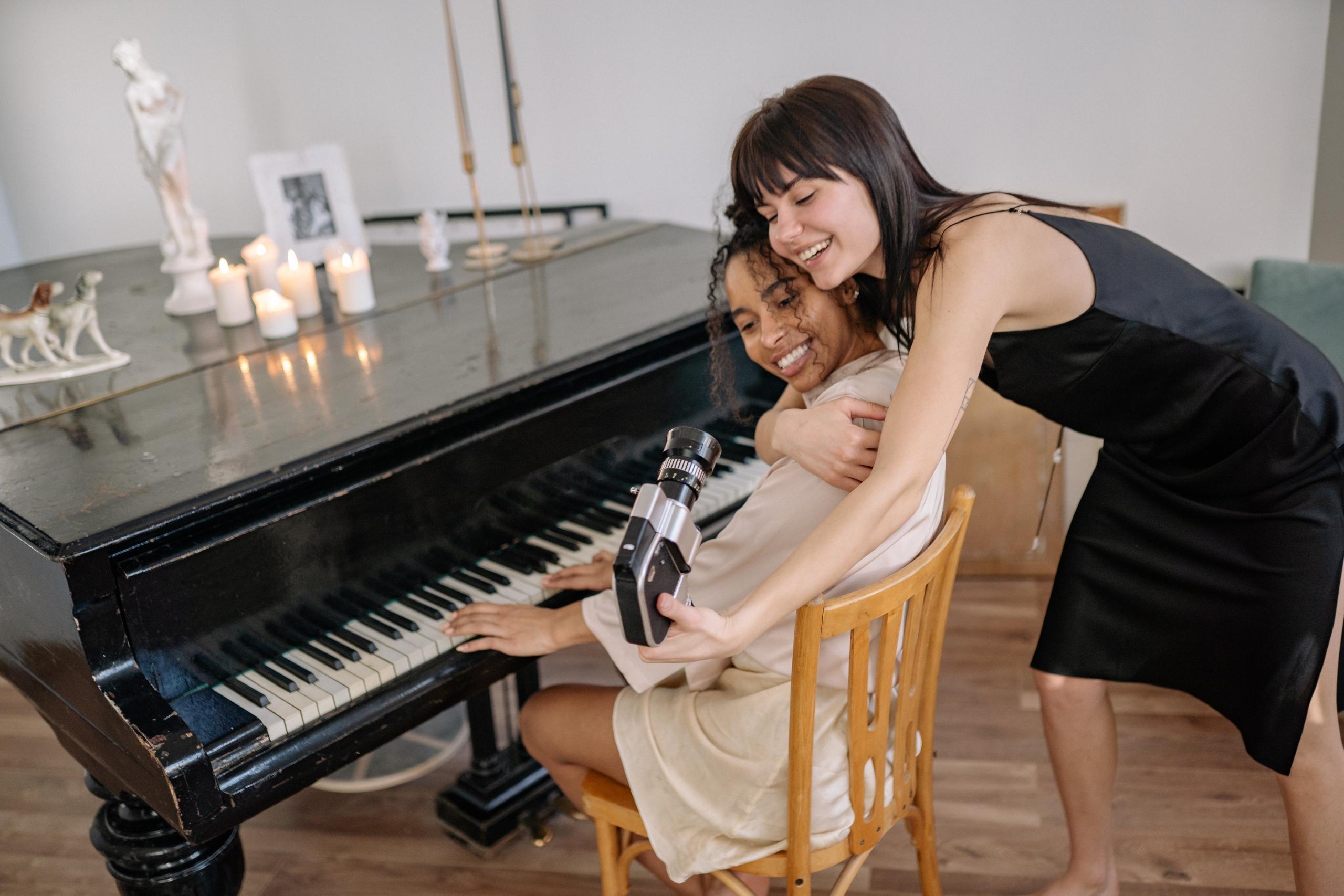 Twee vrouwen filmen zichzelf terwijl ze achter de piano zitten.