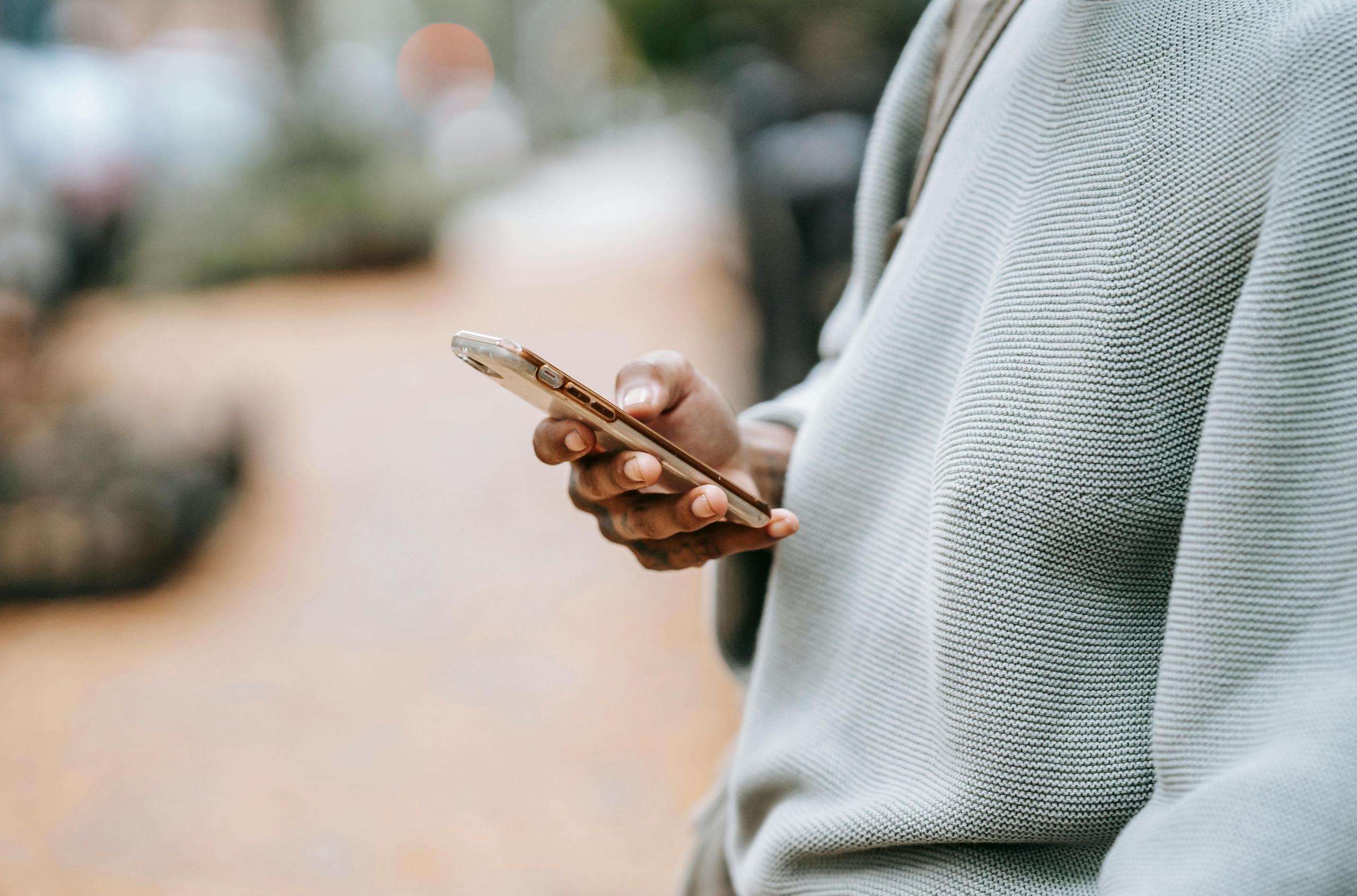 Close-up van een hand die een smartphone vasthoudt.