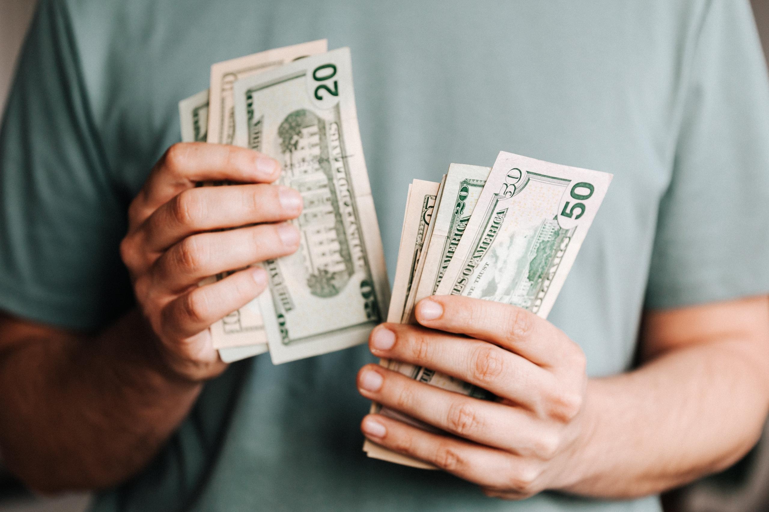Iemand houdt verschillende Amerikaanse dollarbiljetten in de hand.