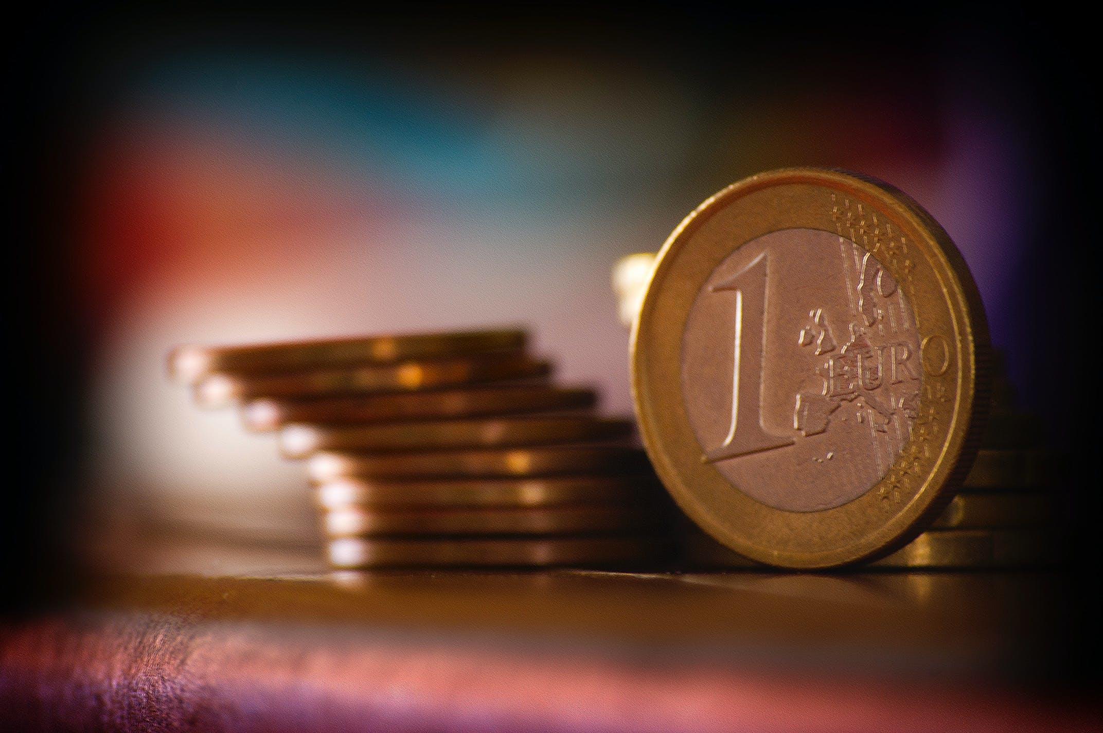Een één euro muntstuk staat voorop met stapels munten op de achtergrond.