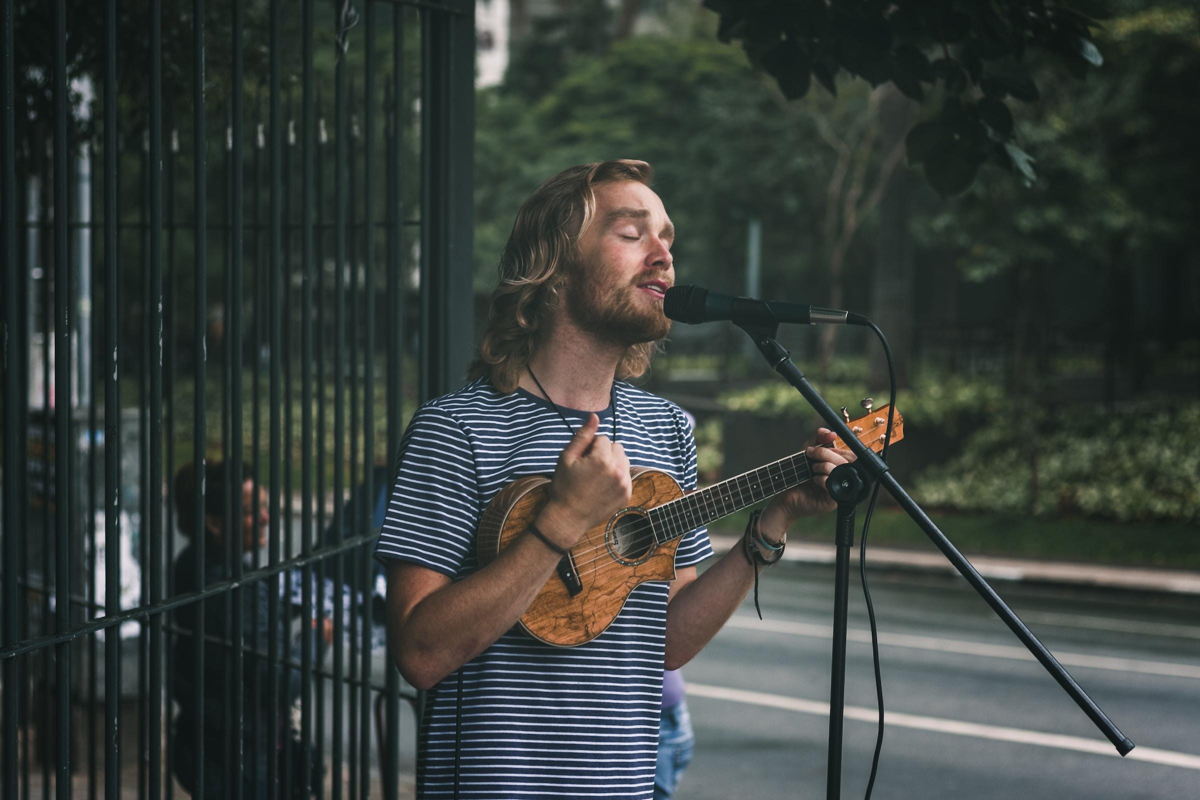 Zingende man met ukelele achter microfoon buiten