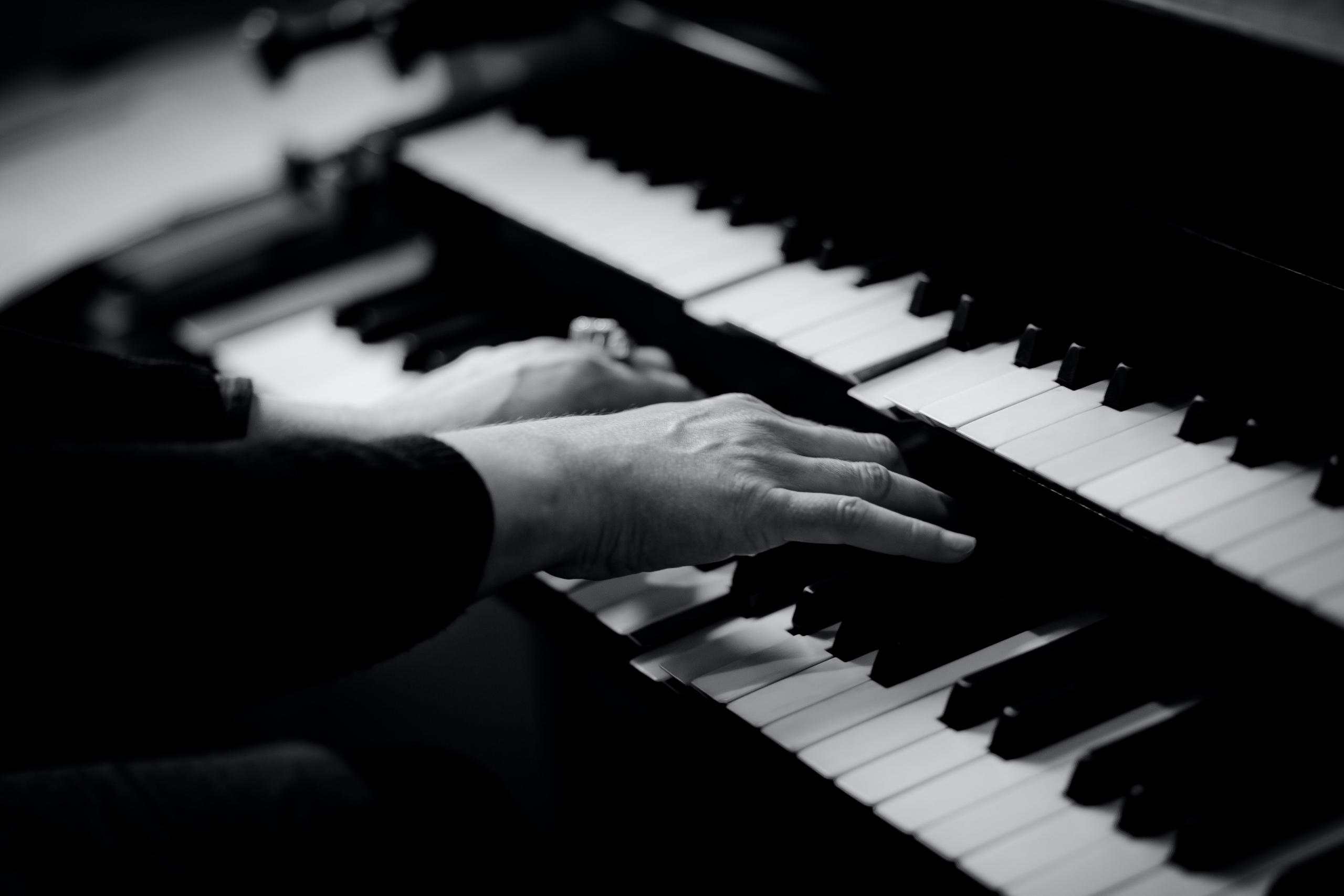 Handen die op een piano spelen.
