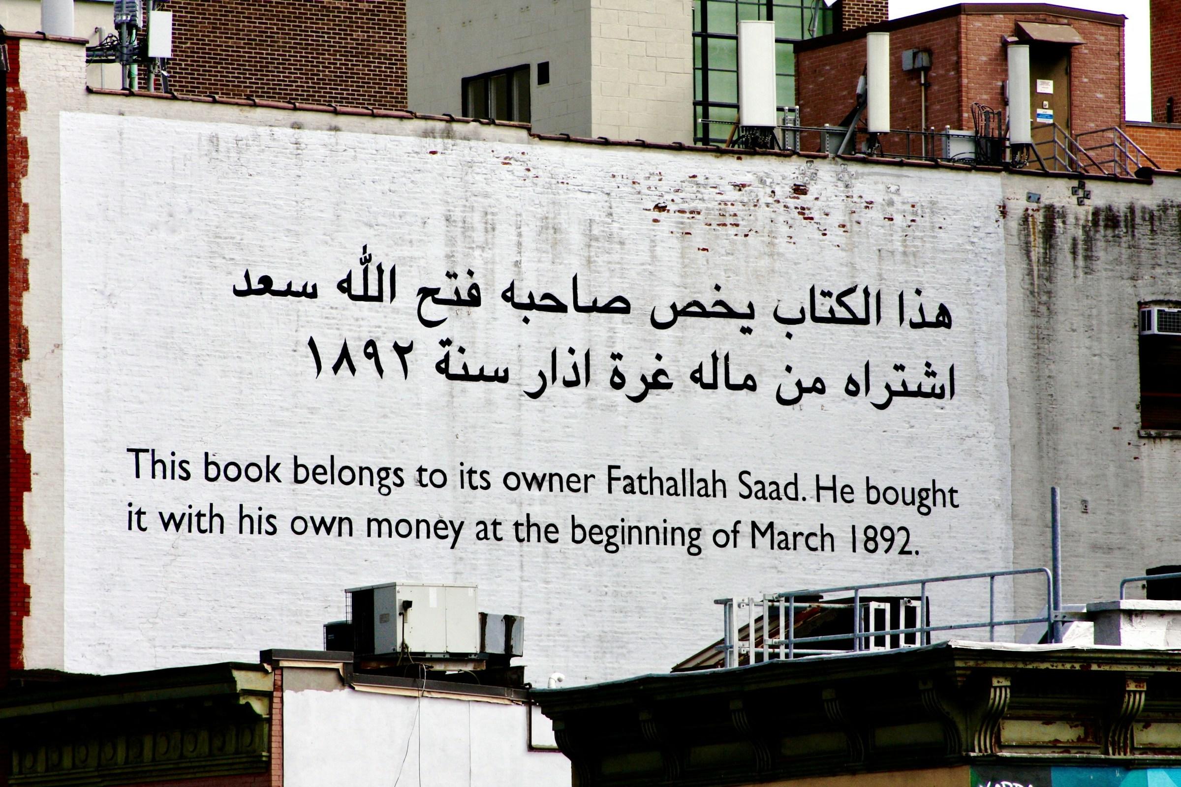 Arabische zin met Engelse vertaling op witte achtergrond op buitenmuur
