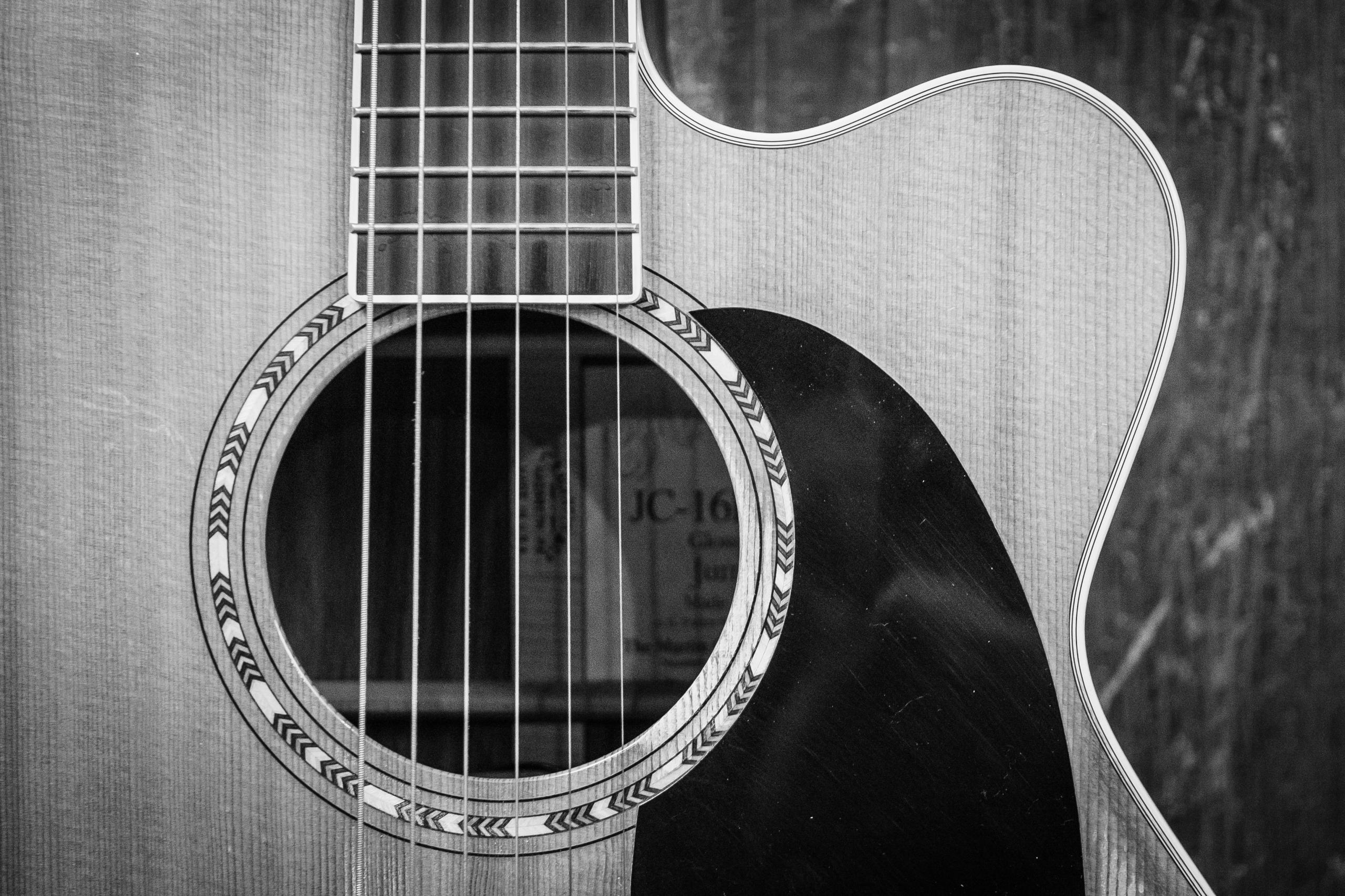 Close-up van een akoestische gitaar in zwart-wit.