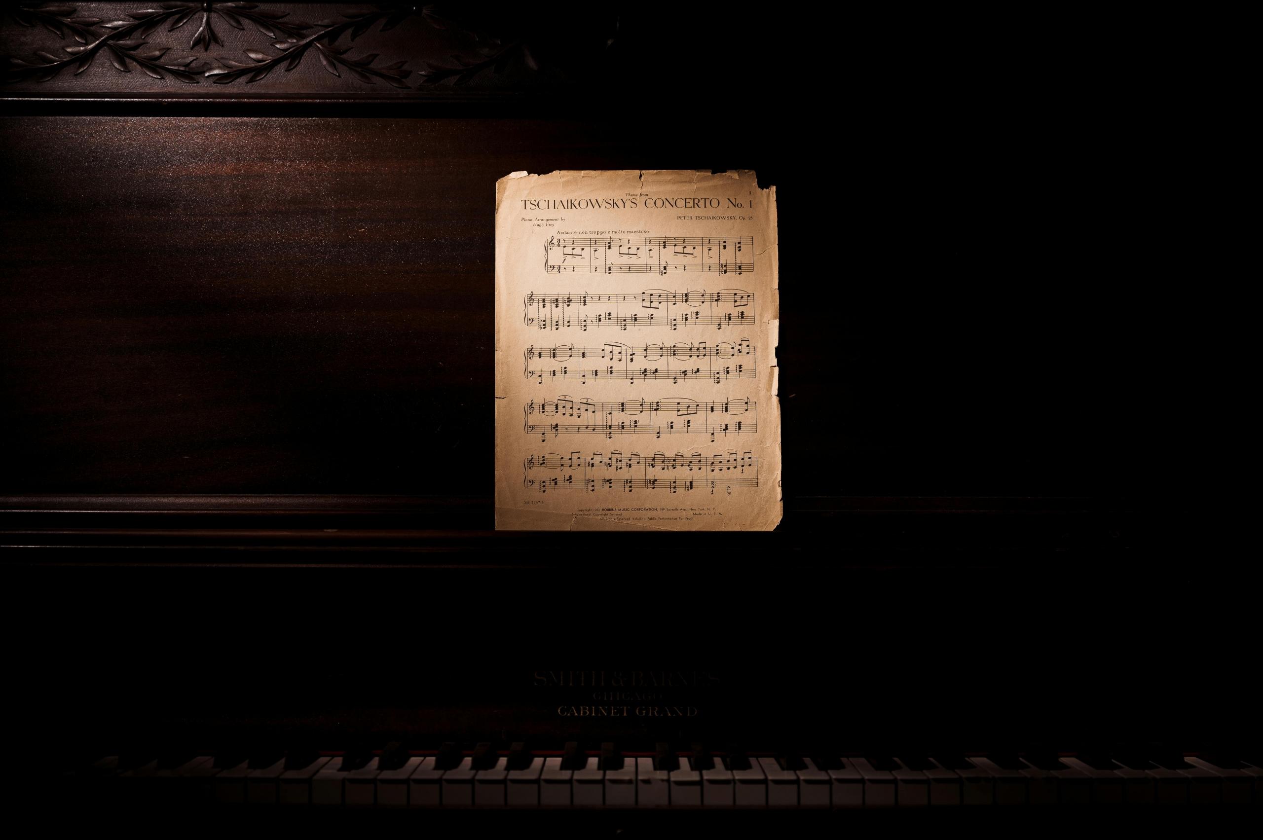 Een oude, vergeelde partituur op de muziekstandaard van een zwarte piano.