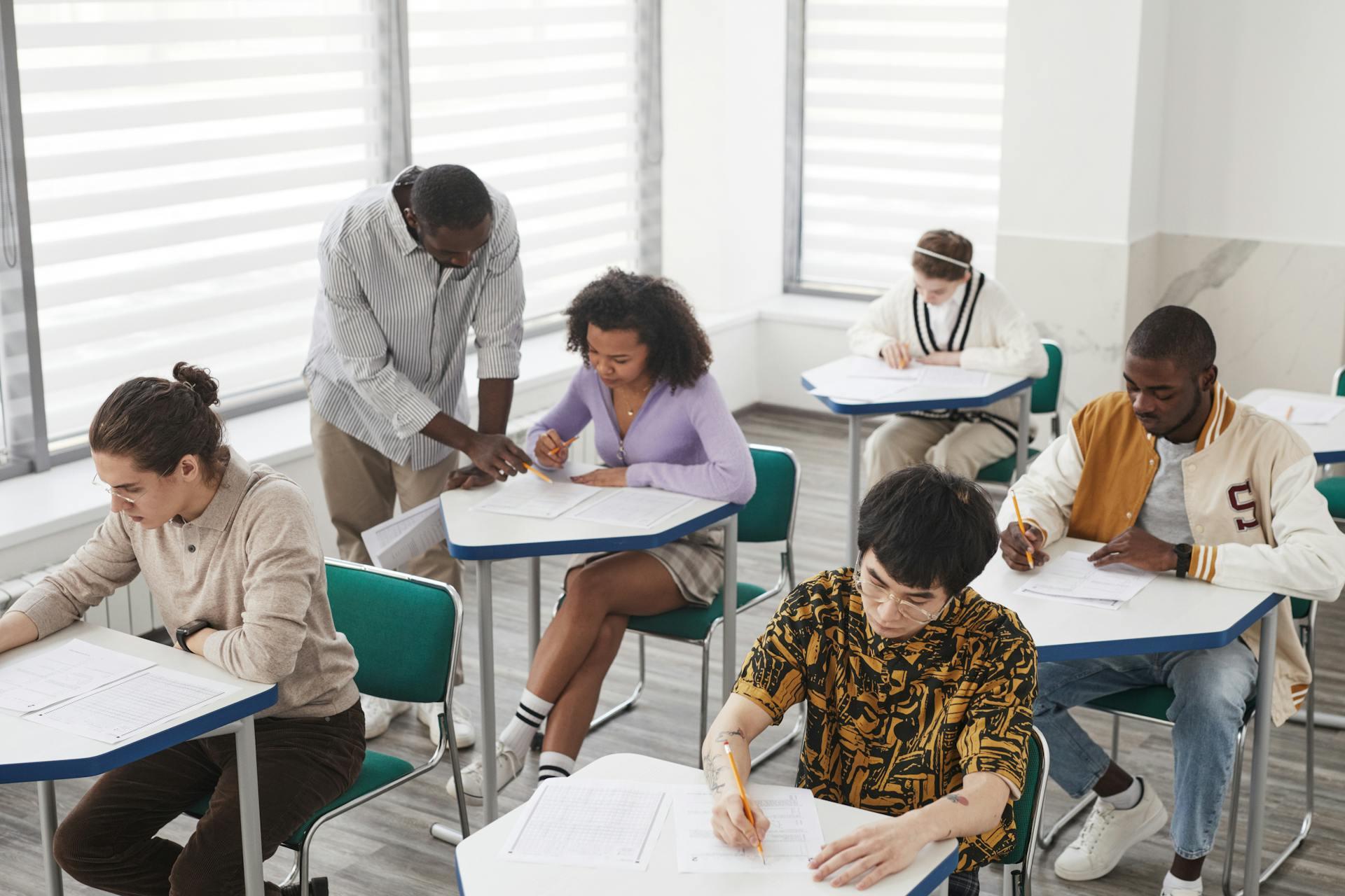 Zittende personen die lezen en schrijven en een staande persoon die iets aanwijst