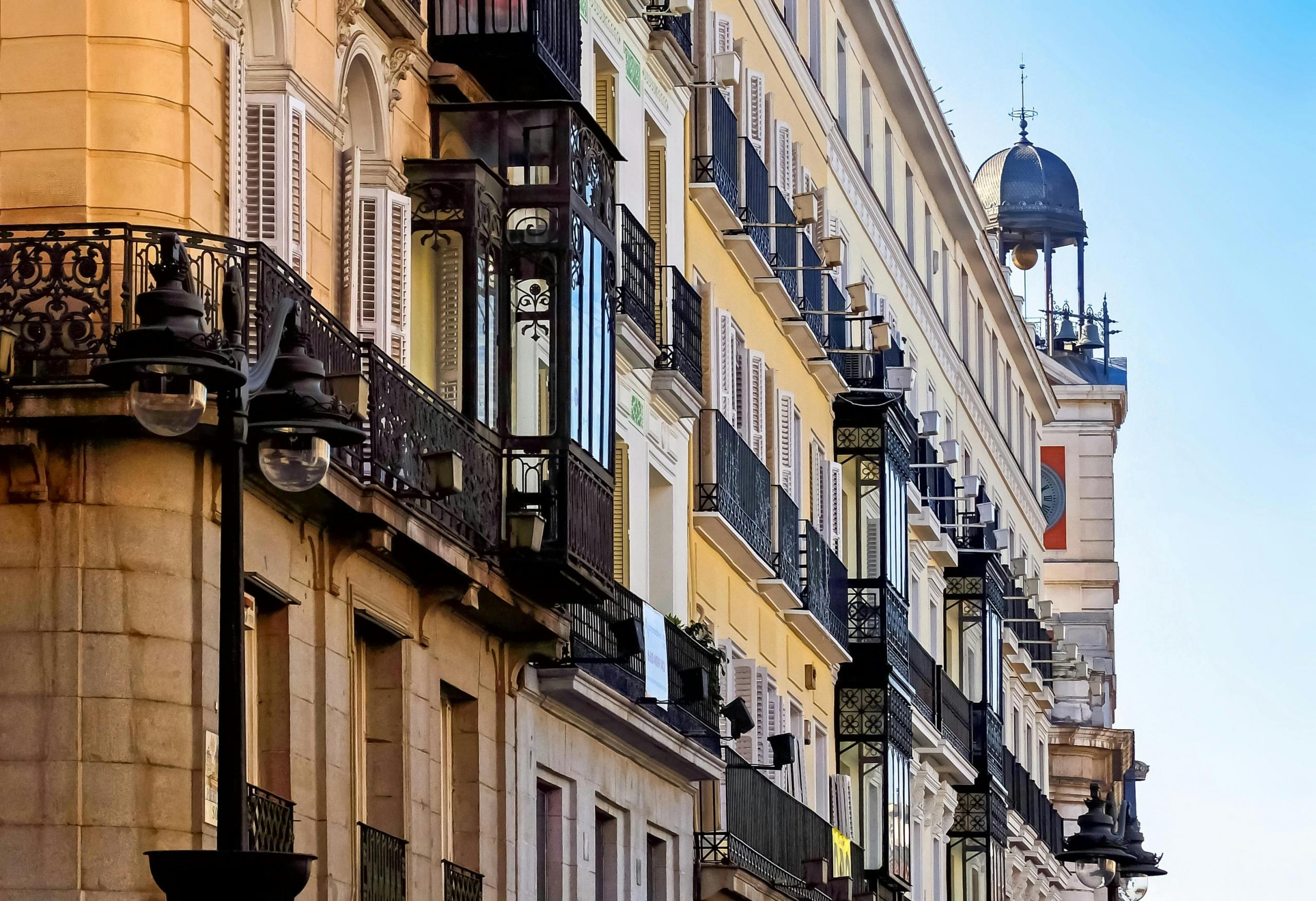 Een straatbeeld van Madrid met traditionele balkons aan klassieke gebouwen en een blauwe hemel op de achtergrond.