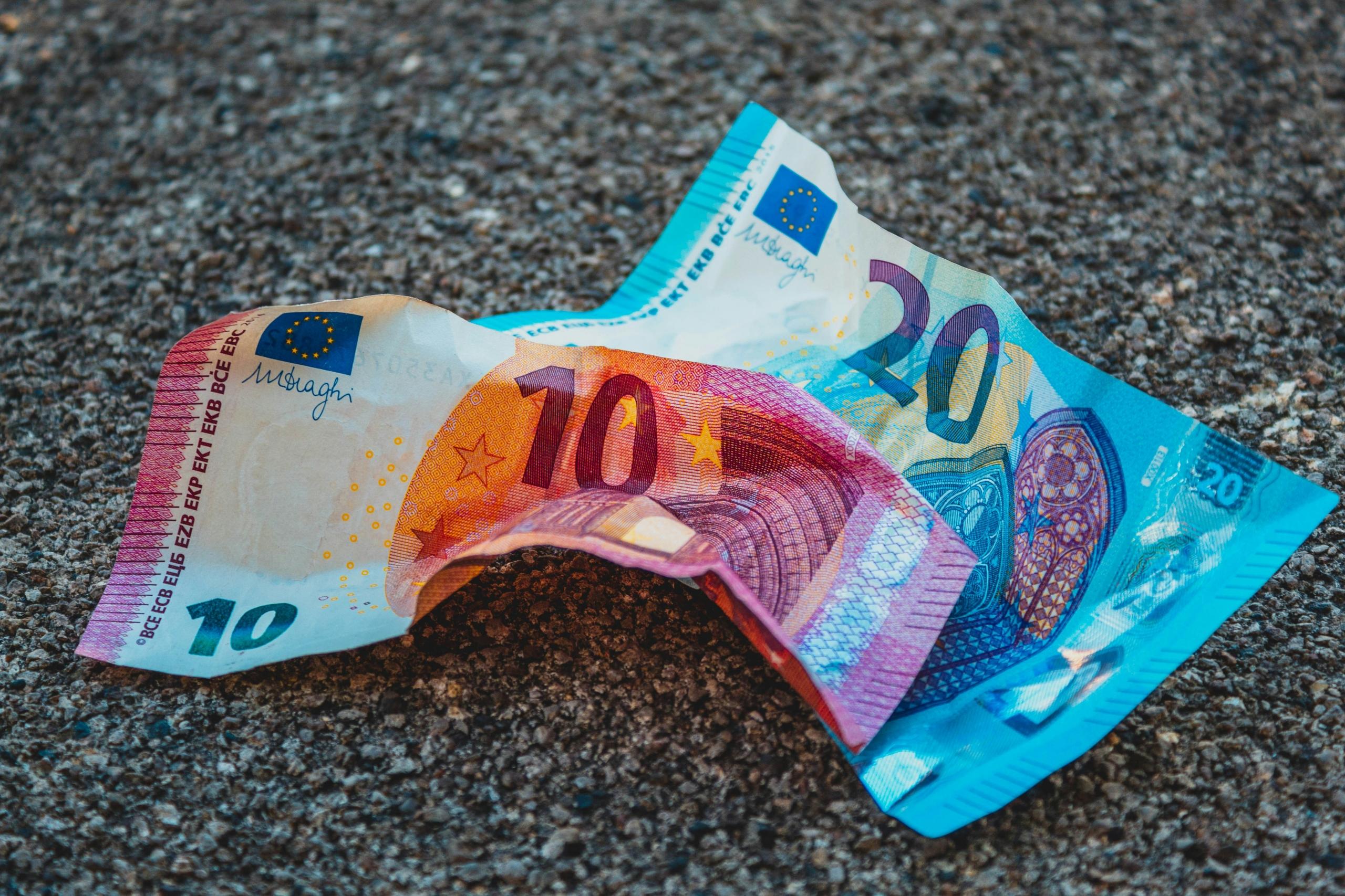Een gekreukt briefje van 20 en 10 euro liggend o op de grond.