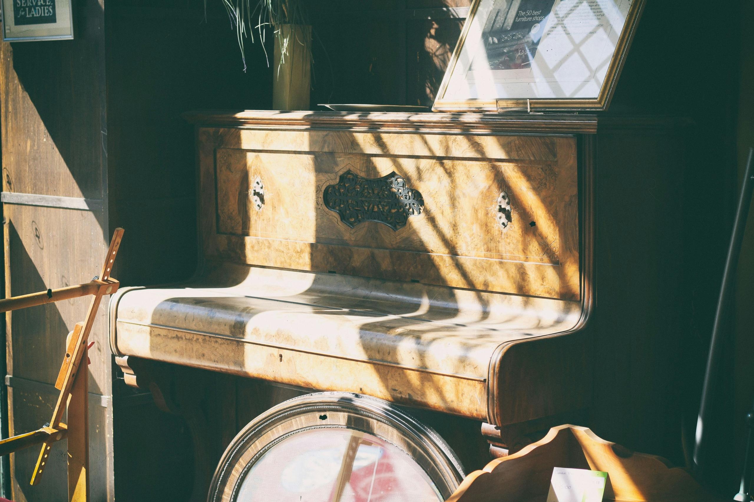 Een antieke piano in een zonovergoten kamer, waarbij het licht speelt over het houtwerk en de versierde panelen.