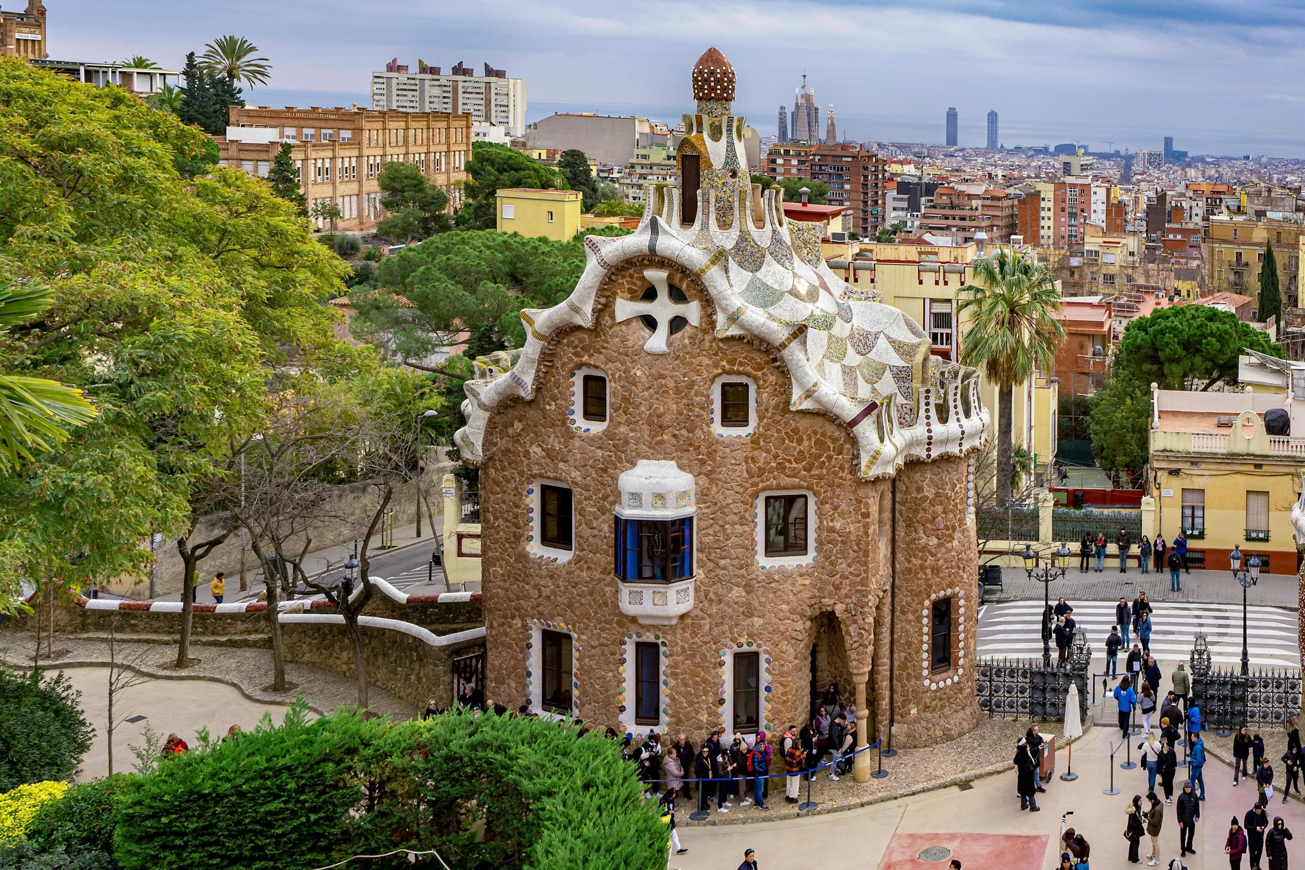 Het beroemde Gaudí-gebouw in Park Güell, Barcelona, met op de achtergrond een panoramisch uitzicht op de stad en de kenmerkende architectuur van Gaudí die te zien is.