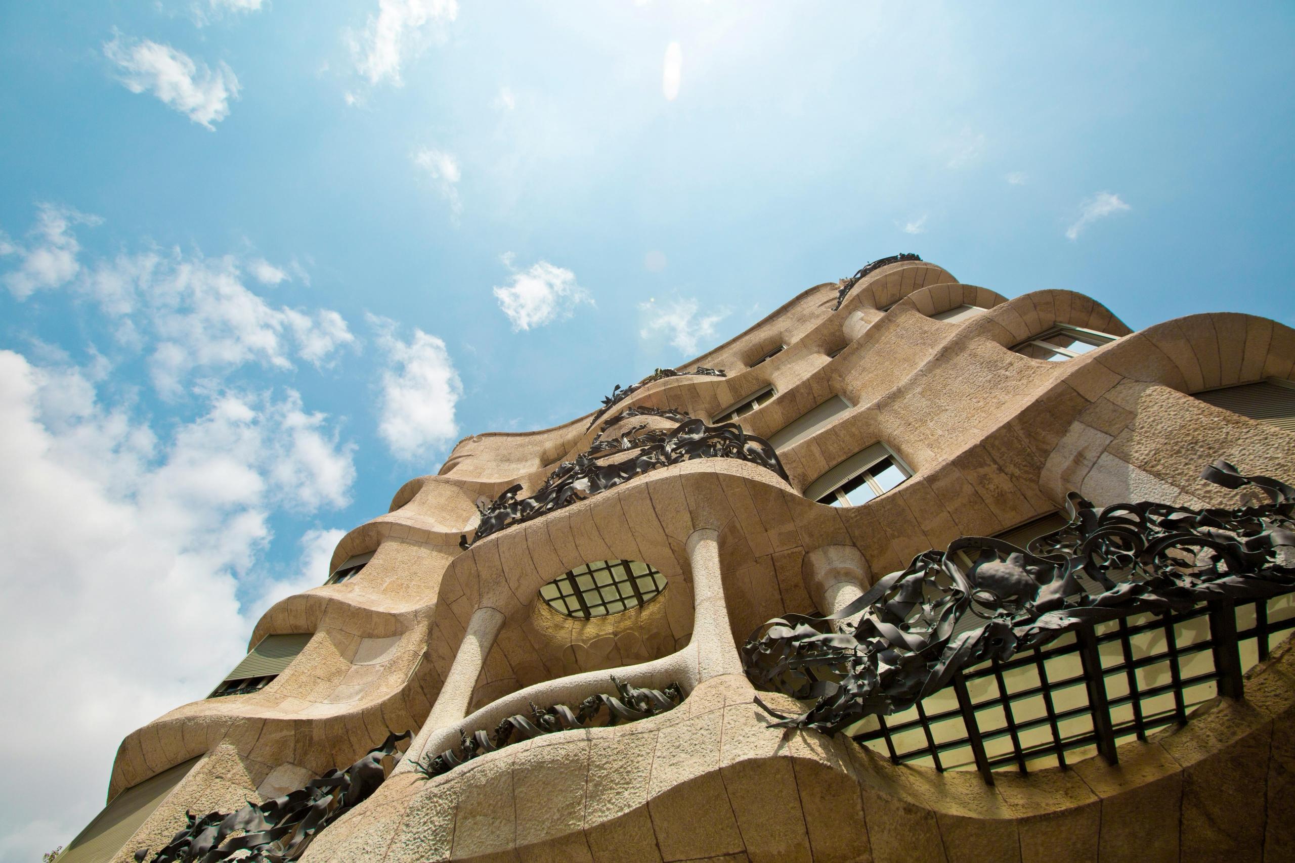 Een golvend gebouw met sierlijk smeedwerk, representatief voor Gaudí's architectuur in Barcelona.