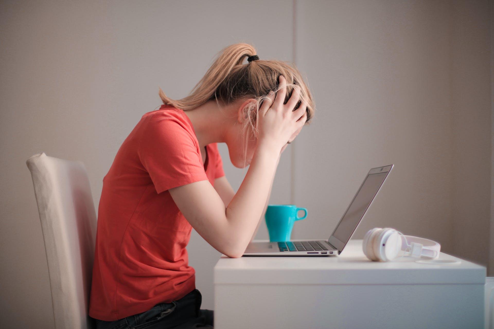Persoon voor laptop met handen in het haar
