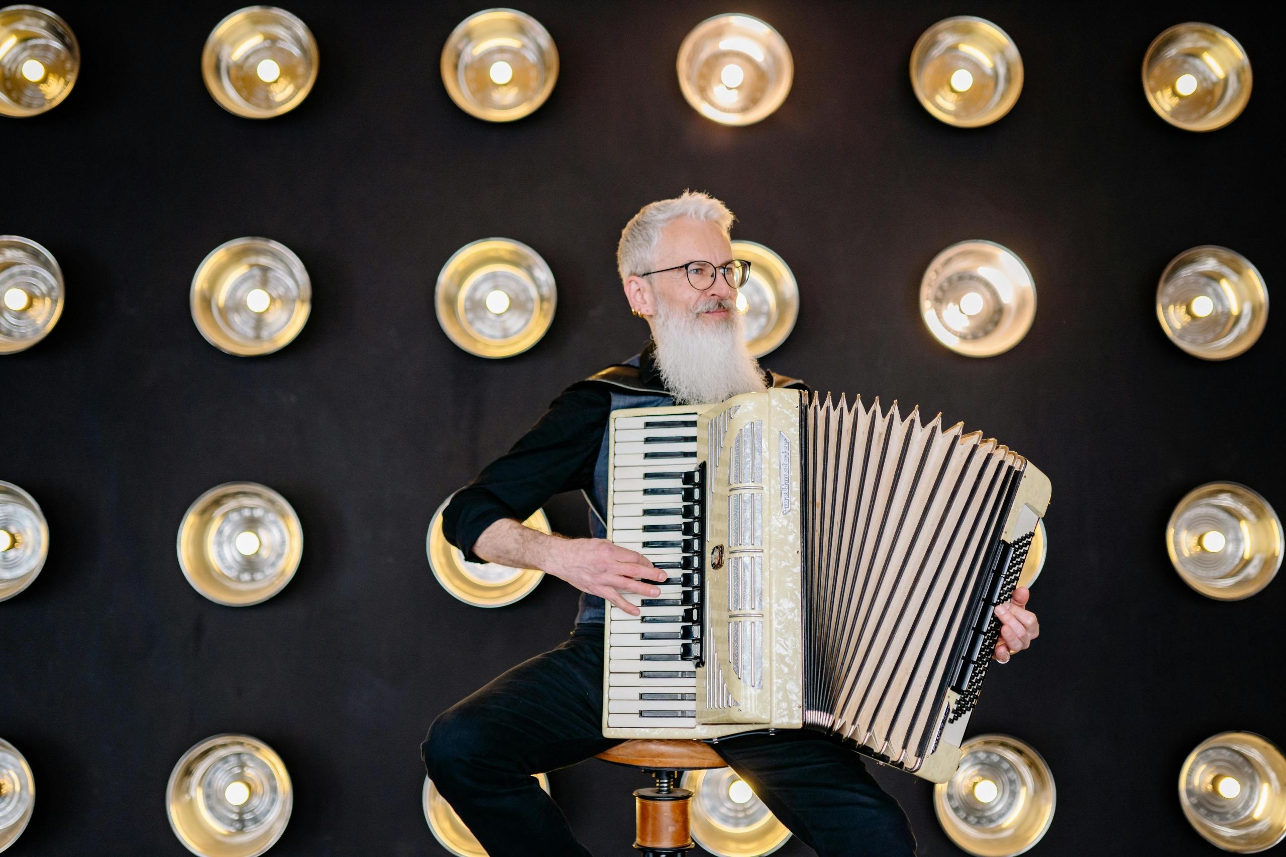 Man speelt accordeon op een stoel met een achtergrond van lampen.
