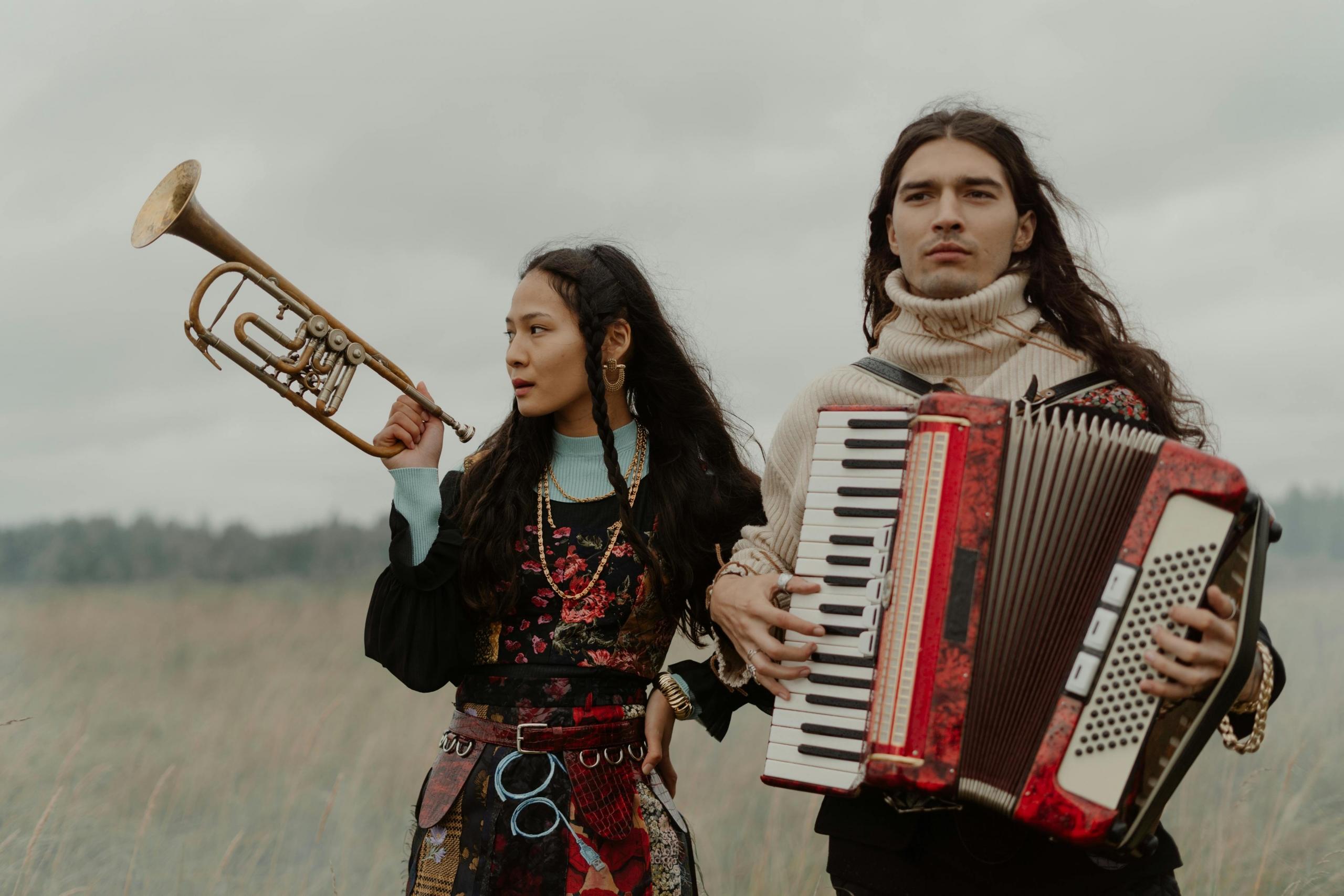 Een duo in een open veld, een vrouw met een trompet en een man met een rode en zwarte accordeon.