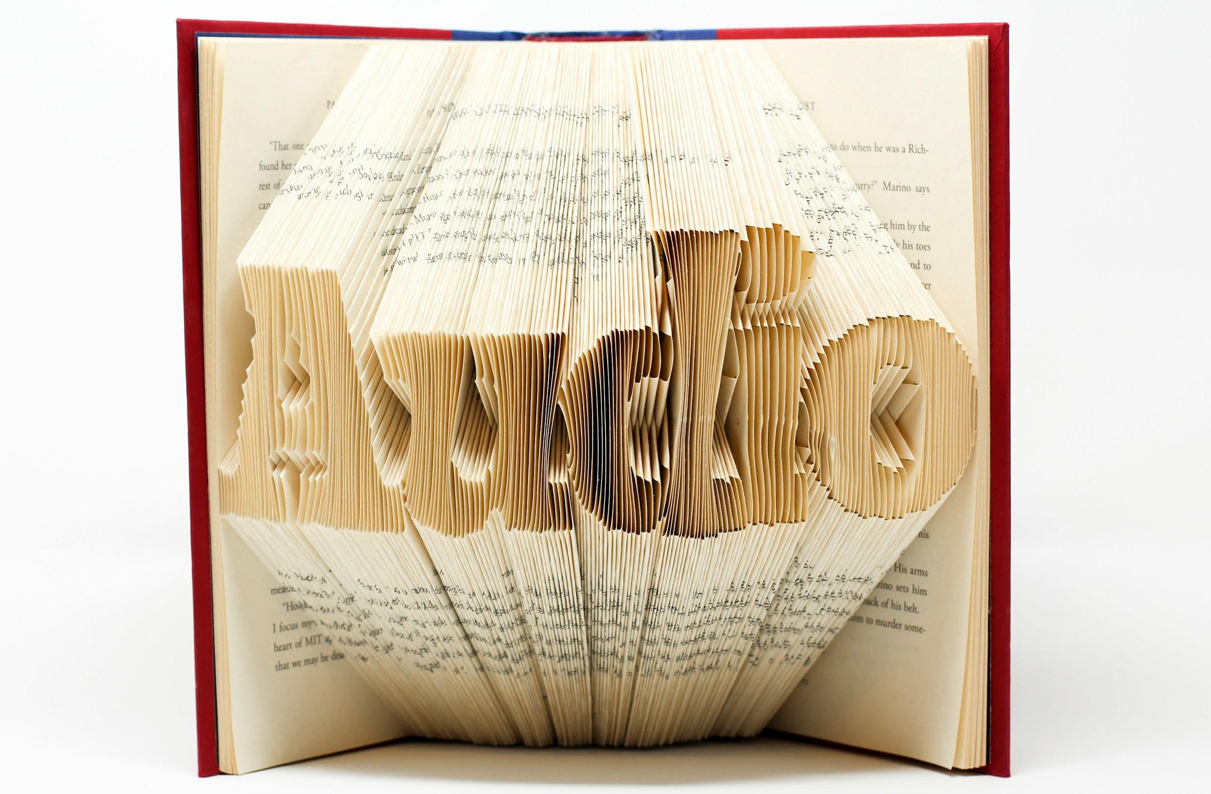 Opengeslagen boek met gevouwen bladzijden die het woord audio vormen