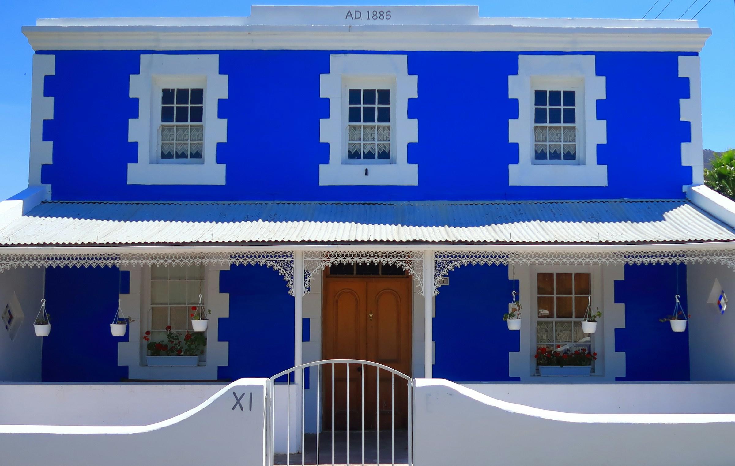 Een blauw en wit huis met een bruine deur