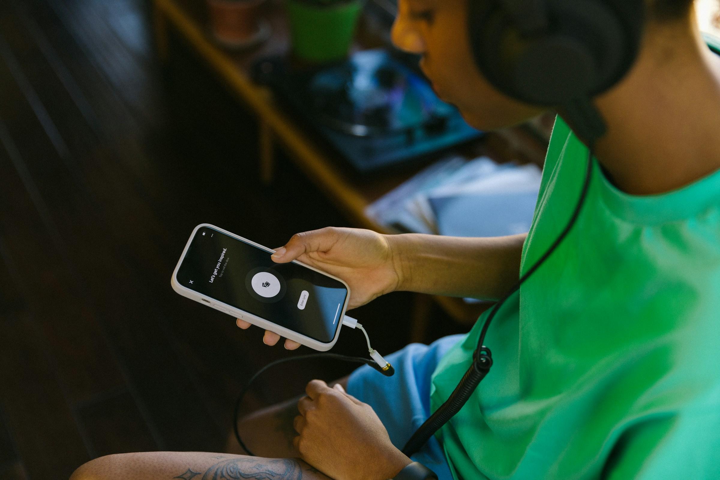 Zittende persoon met koptelefoon op en IPhone in hand